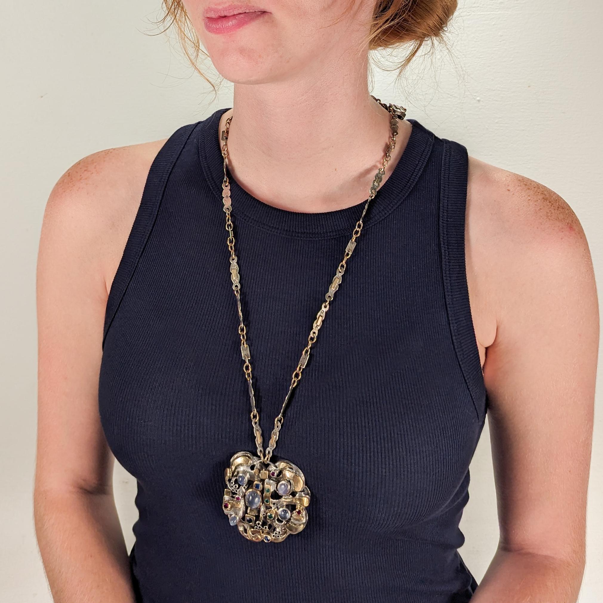 A fine Modernist pendant necklace.

By the New York City Modernist female goldsmith Resia Schor. 

In sterling silver, 14k gold, and bezel-set with multiple gemstones

Comprising a large pendant and a mixed metals gold and silver hand-built chain