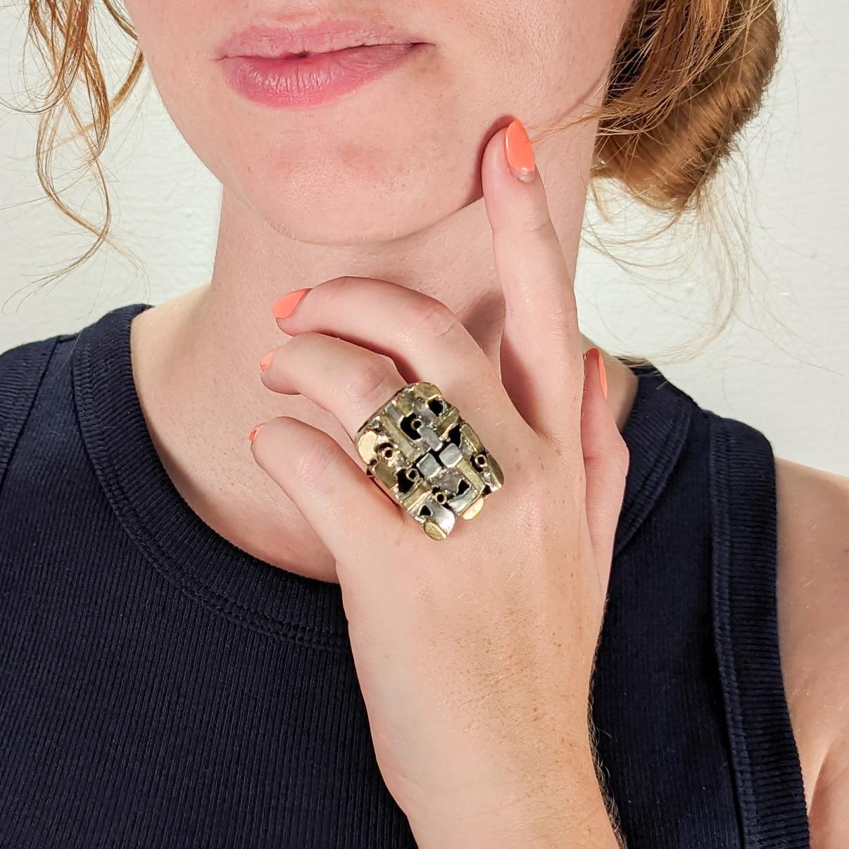 A fine Modernist ring.

By the New York City Modernist female goldsmith Resia Schor. 

In sterling silver and 14k gold.

Comprised of a cubist or tableau-like head of mixed gold & silver elements and set with a wide gold band.

Designed with