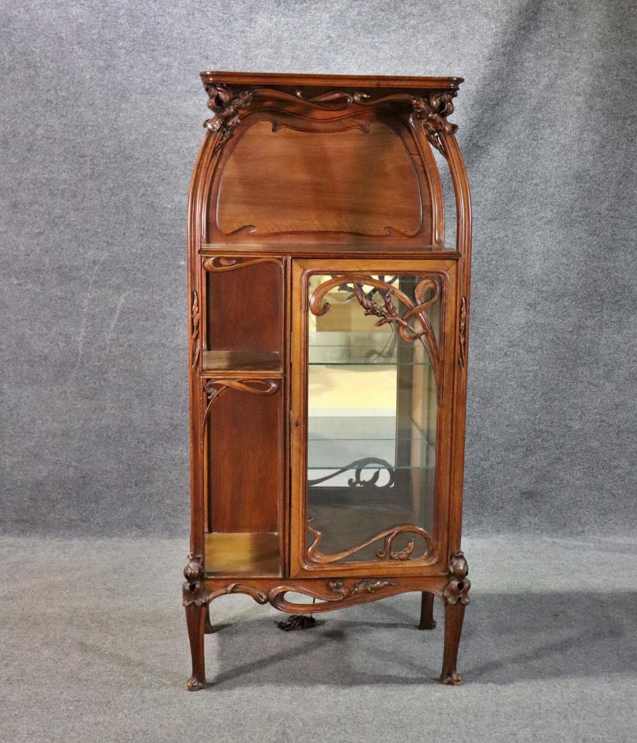 Wood. One glass door containing 2 glass shelves. Mirrored back. Carved. Lighted. Metal label on bottom edge of interior door frame. 63 1/4