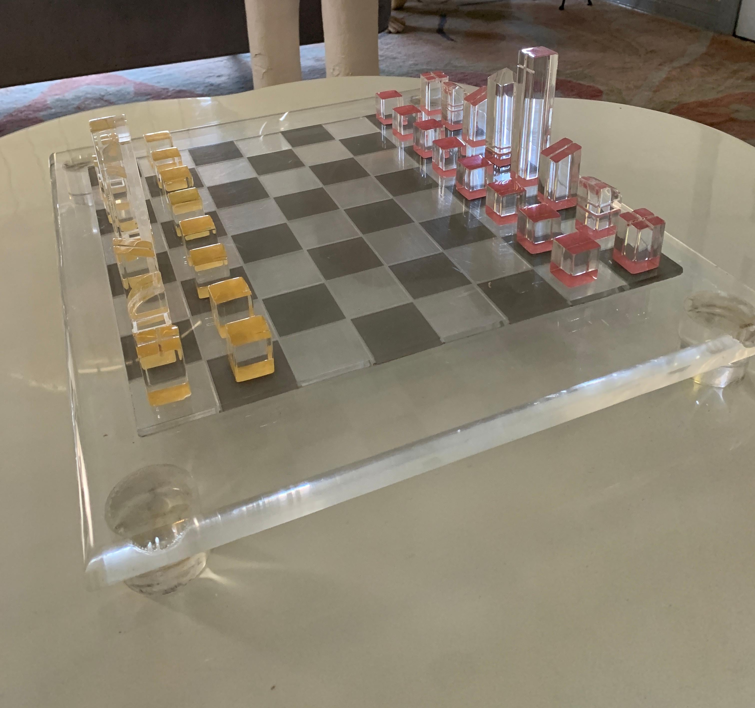 A large, and quite spectacular acrylic MidCentury chess set. The board is very thick and substantial on four thick disk  legs, the pieces are defined by a painted yellow or orange color on the bottom. All pieces are uniquely scored or cut to