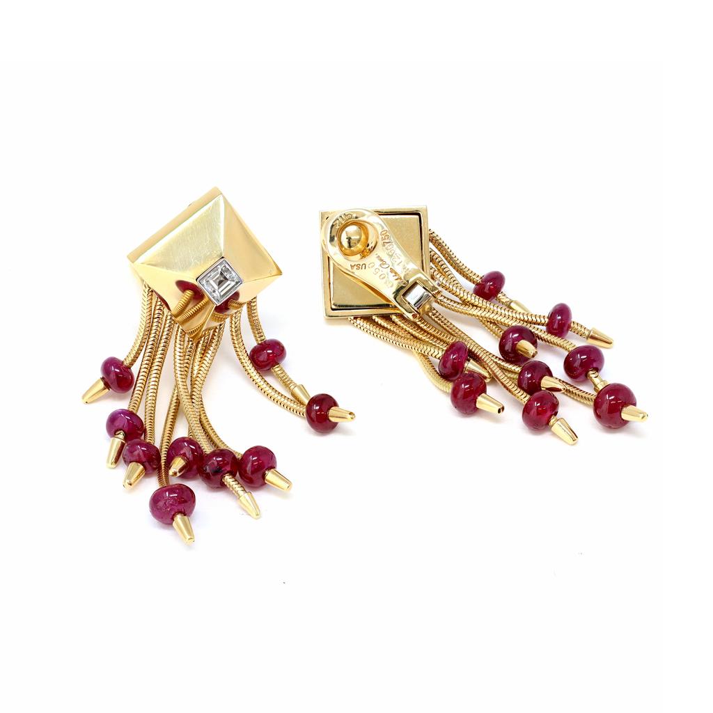 A pair of elegant and playful pair of dangling earrings by the famous house of jewelry Aletto Brothers. The skillfully handmade clip on earrings are set in 18 karat yellow gold, they feature polished Ruby beads dangling from a pyramidal top with an