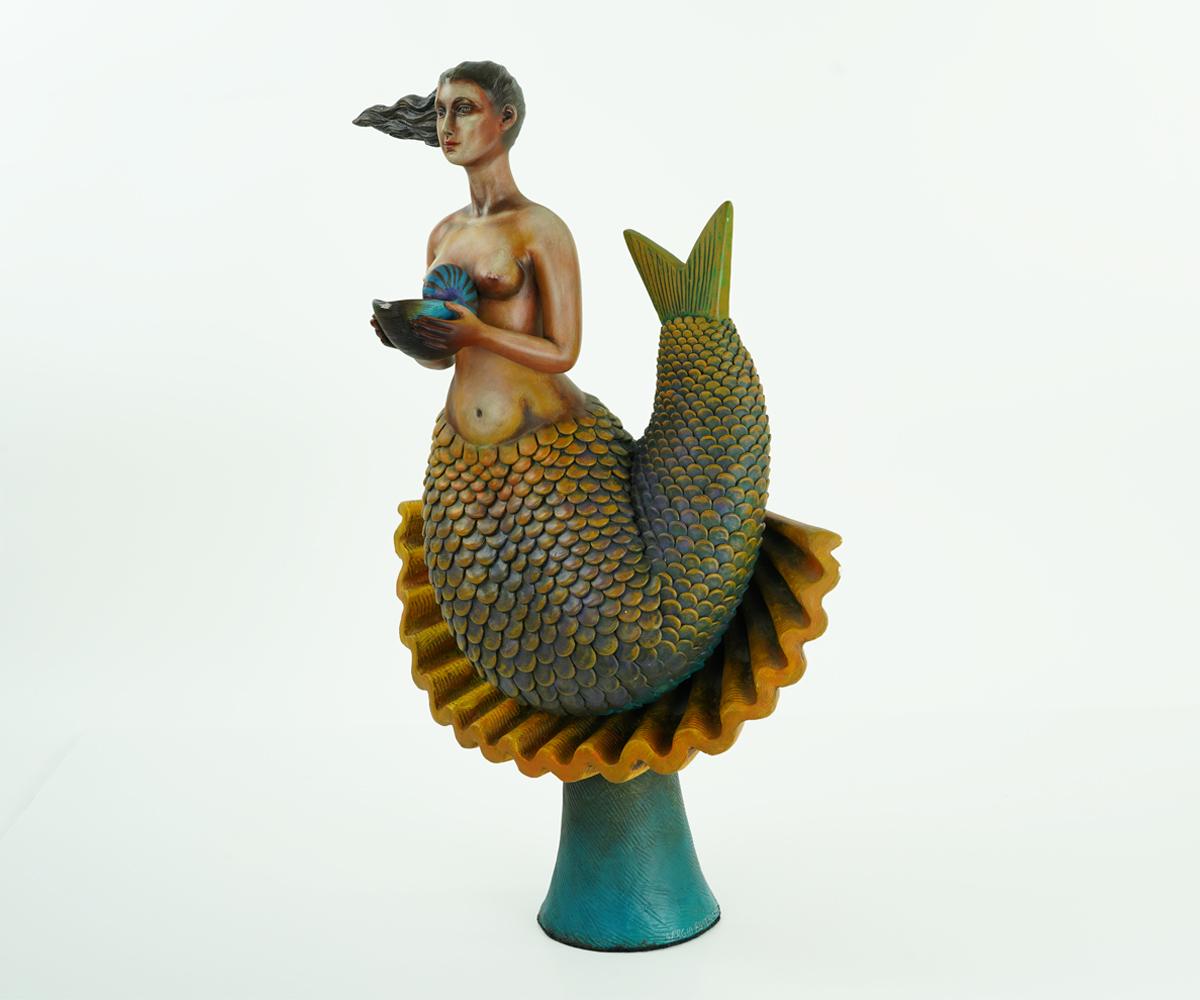 Mermaids were one of Sergio Bustamante's favorite and most popular subjects and this is one of his most collectible pieces as a result. The mermaid rests upon a shell base mounted on a dark turquoise stand and is holding a smaller shell in her arms