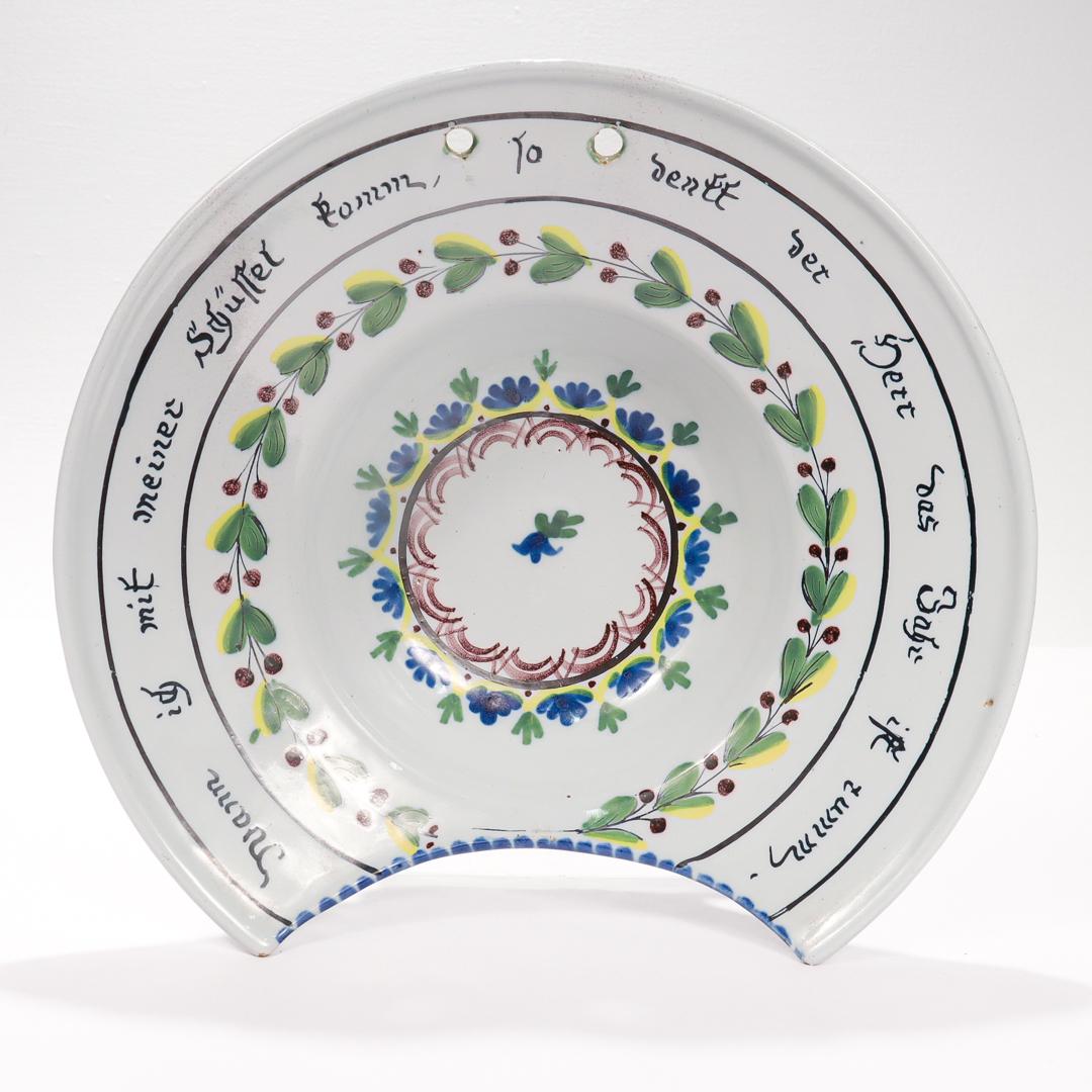 A fine antique German fayence (or faience) pottery shaving bowl.

Marked for Wallendorf.

In a white ground tin-glazed pottery richly decorated with blue, green, yellow and brown underglaze flowers and foliage.

With a cutaway to the rim for the