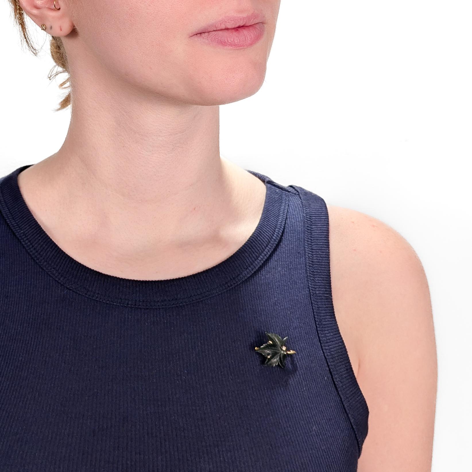 A fine, signed antique leaf brooch or pin.

In 14k yellow gold.

With a carved, 5-point variegated leaf (likely a Maple leaf) in green jade (nephrite) that is prong-set on a gold mount and set with a small round white accent diamond.

Marked with a