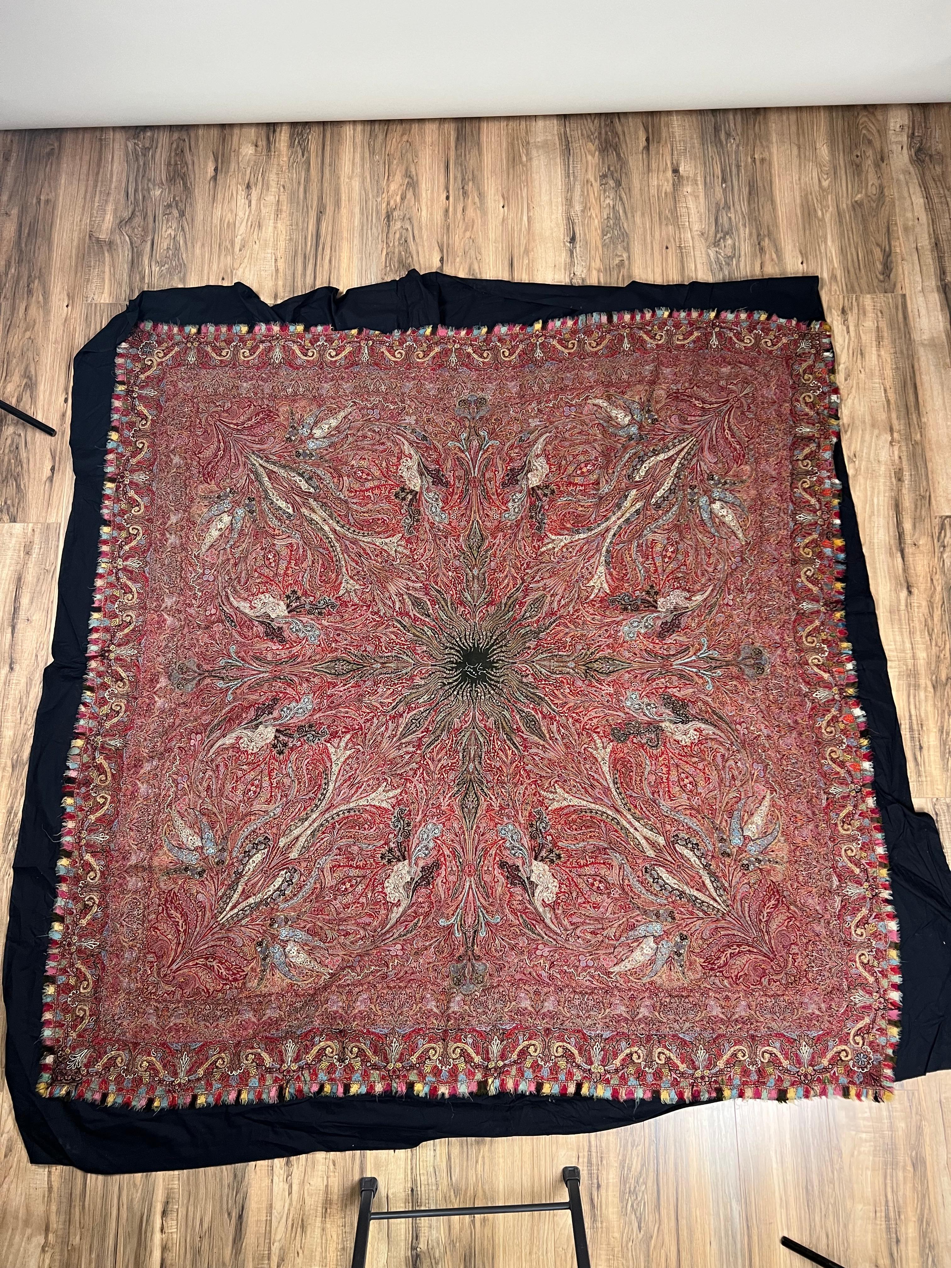 Ce châle kani antique du Cachemire présente un puissant médaillon en forme d'étoile qui rayonne vers l'extérieur dans des arrangements floraux et paisley complexes, tissés de façon magistrale dans de riches tons de rouge, de bleu, d'ivoire et d'or.