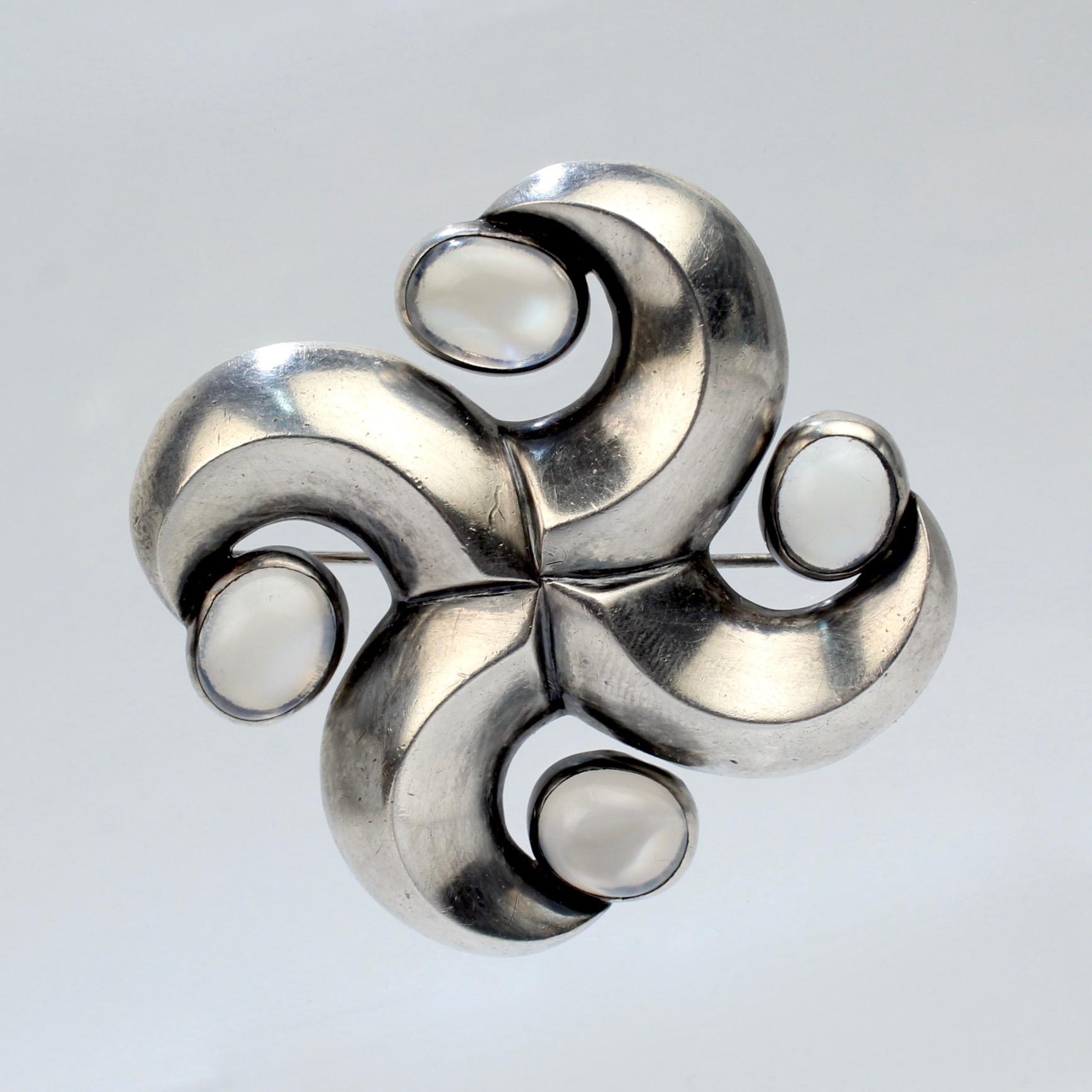 A fantastic swirled star or pinwheel brooch by Antonio Pineda. 

In sterling silver and set with moonstone cabochons. 

Antonio Pineda was a renowned Mexican silversmith and jewelry maker. His jewelry is among the most coveted Mid-Century Mexican