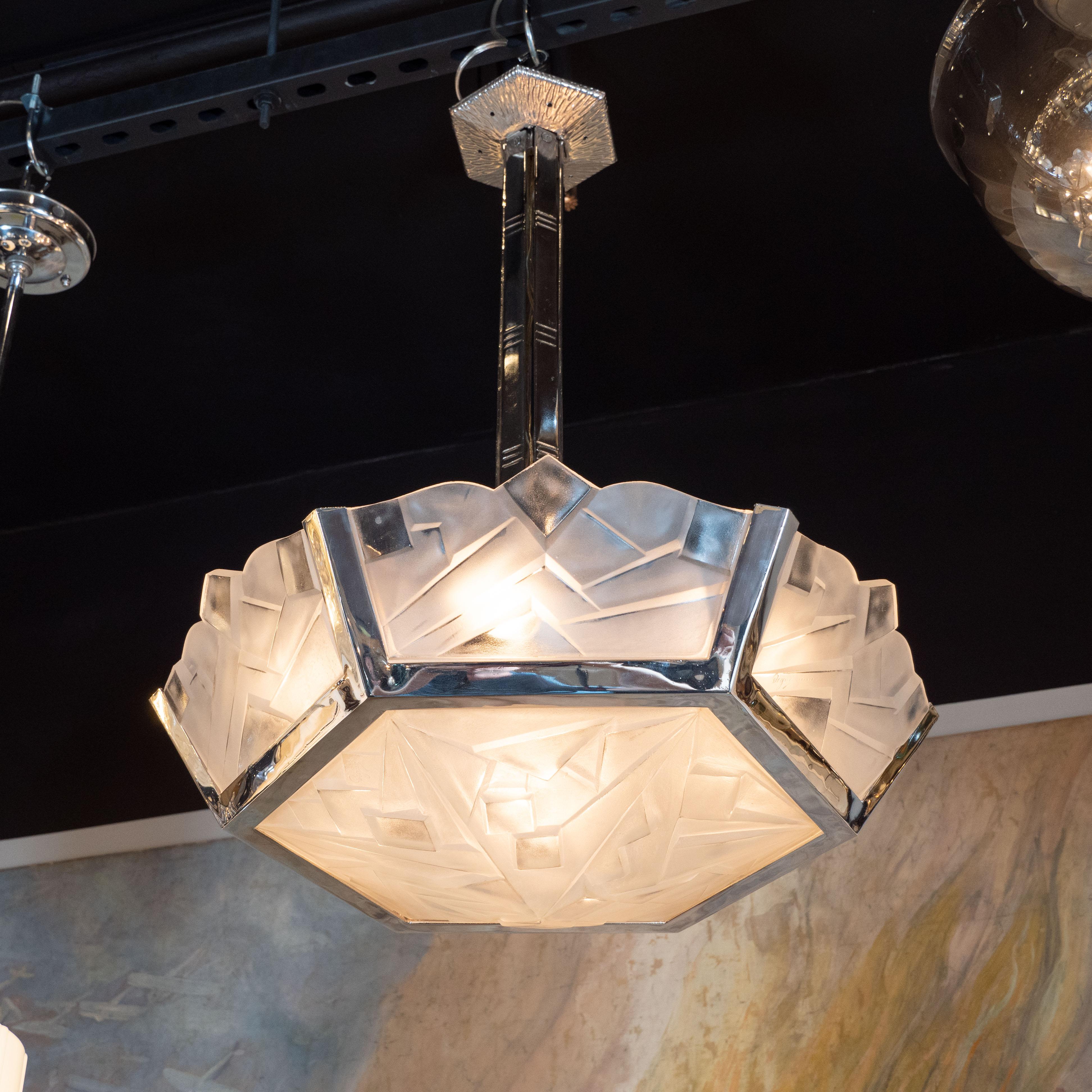 This gorgeous Art Deco skyscraper style cubist frosted glass and nickeled bronze chandelier was realized by the fabled French maker Degué, circa 1930. It offers a hexagonal bottom shade etched with a variety of cubist geometric forms and five