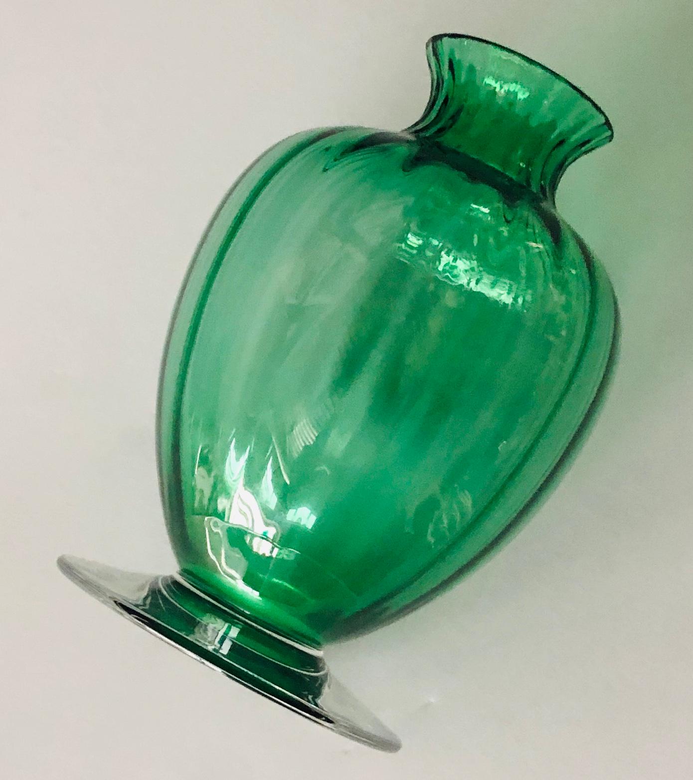 Offered is a signed Mid-Century Modern signed Baccarat elegant small baluster form bud vase of emerald green ribbed crystal and clear spreading foot, with acid etched maker's mark on the bottom and Baccarat sticker. This little piece would add a