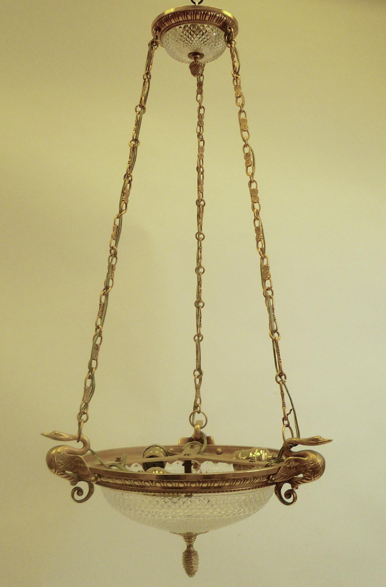 This hanging fixture features neoclassical motifs, including egg and dart moulding and swan finials. The crystal is finely cut in a diamond pattern with stepped borders.