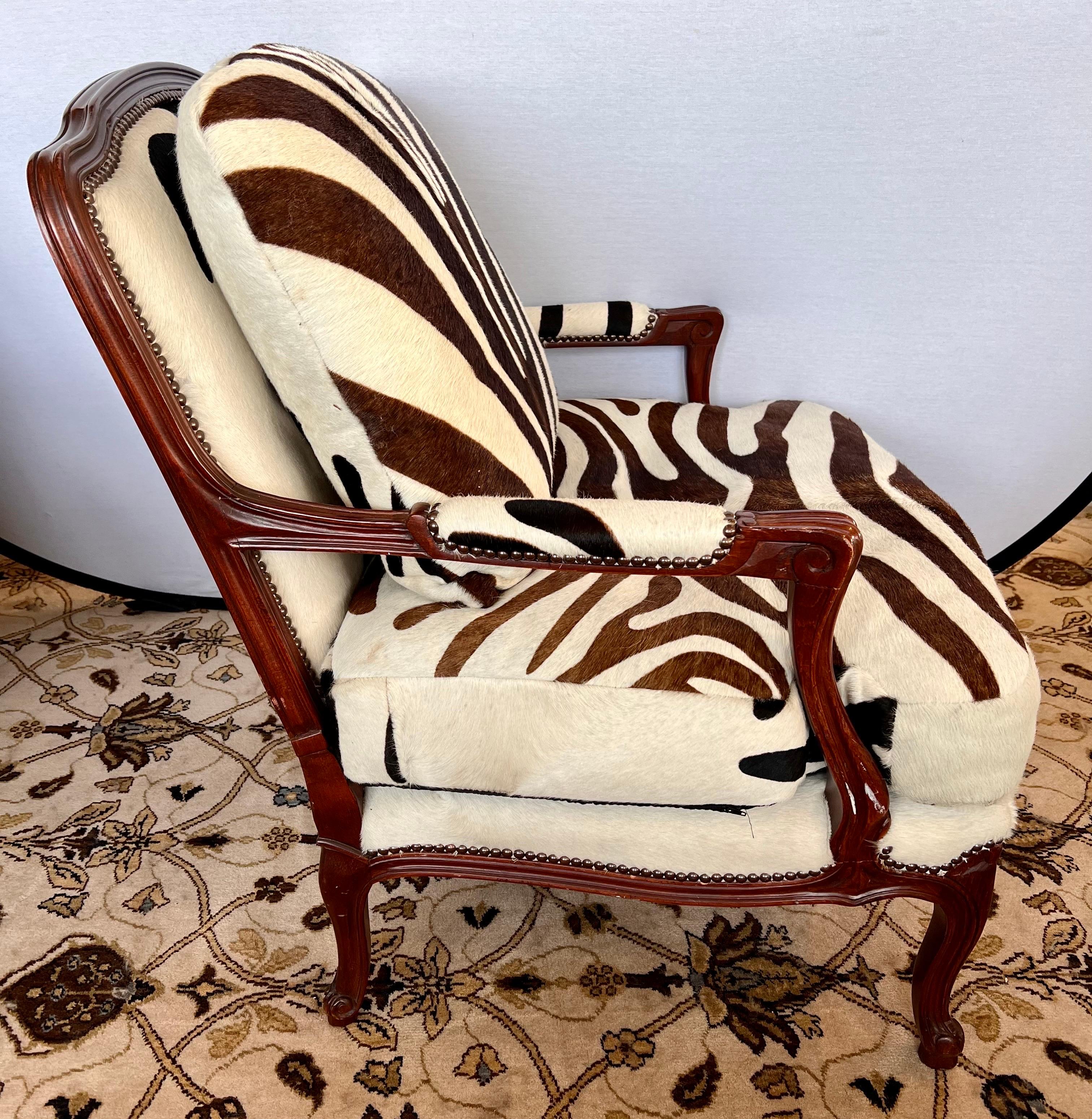 Stunning, signed Baker Furniture mahogany bergere chair with brass nailheads and newly upholstered in a real calfskin with zebra print. What makes this chair extra special is that there are two hides used, on with browns and one with blacks, see