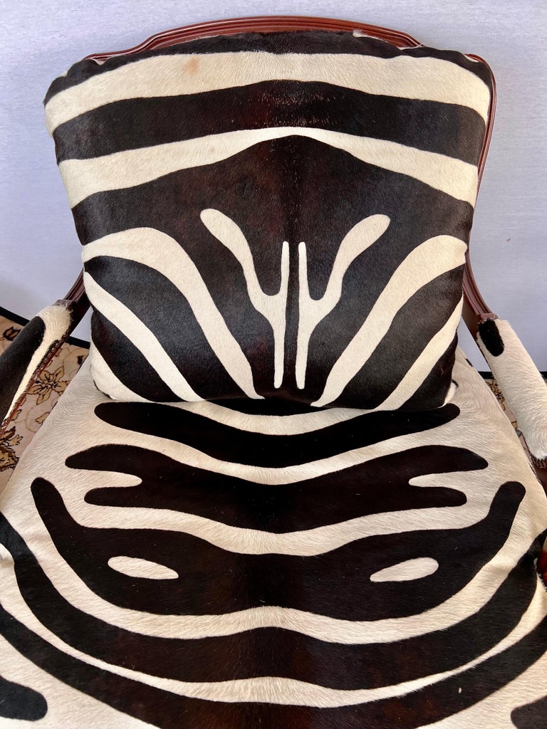 Stunning, signed Baker Furniture mahogany bergere chair with brass nailheads and newly upholstered in a real calfskin with zebra print. What makes this chair extra special is the spectacular hide that was used with black being the prominent color,