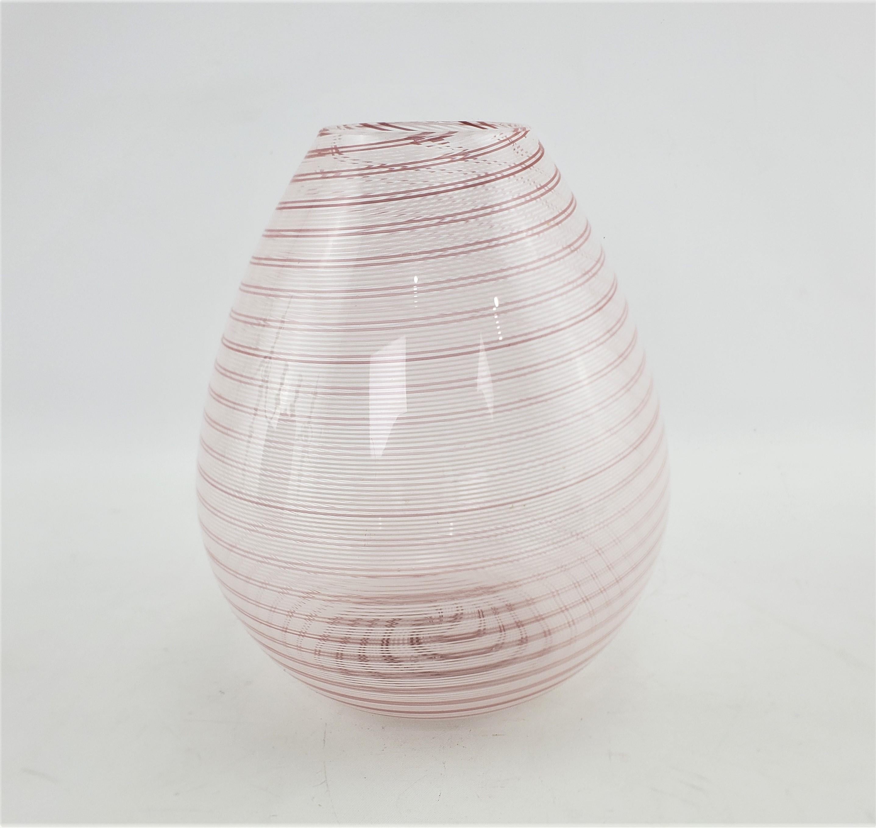 Ce vase en verre d'art signé a été réalisé par la célèbre société Barovier & Toso de Murano, en Italie, vers 1965, dans le style moderne du milieu du siècle. Le vase est en verre transparent avec des rubans tourbillonnés de bandes blanches et rouges