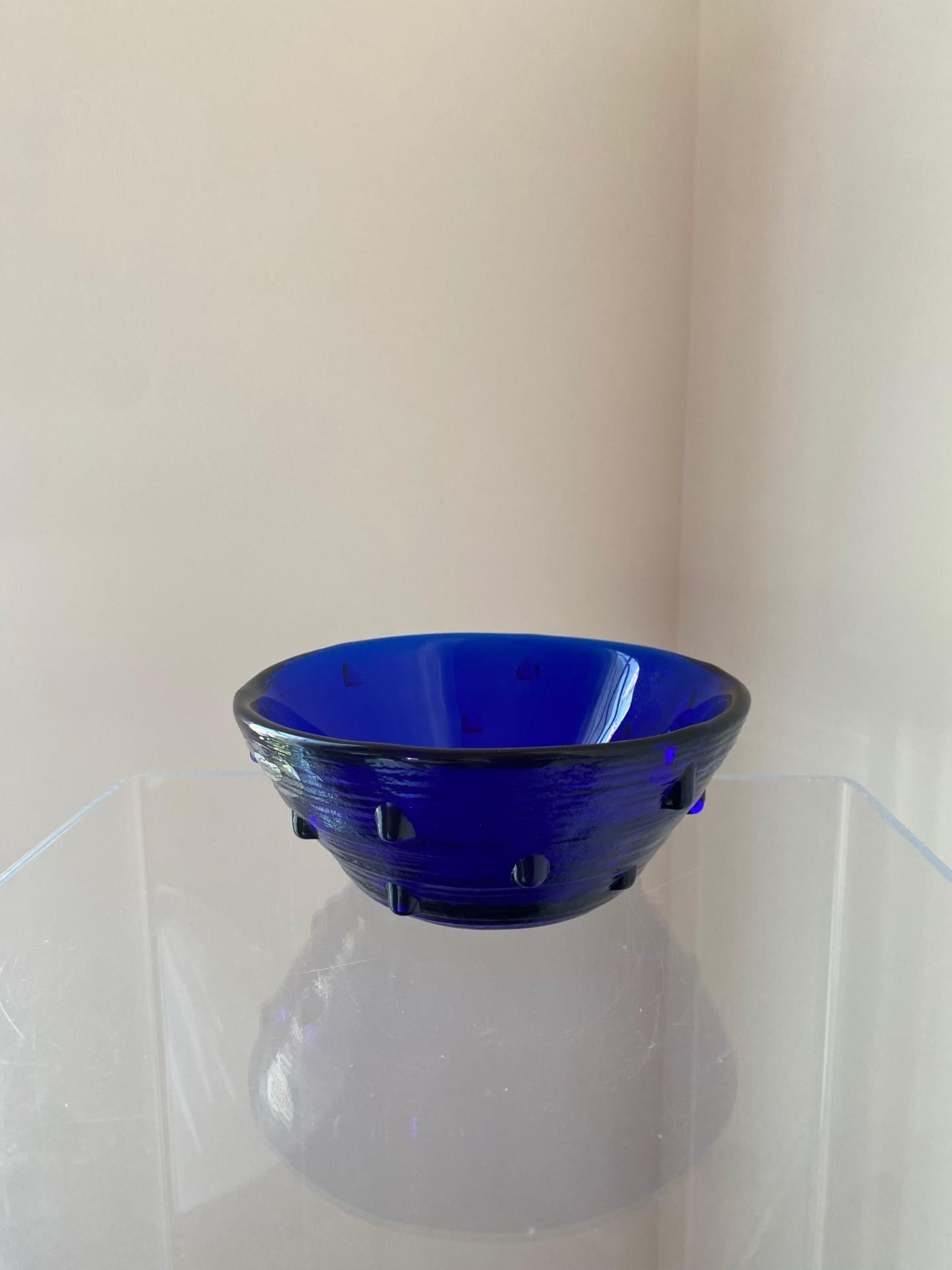 Beautiful handcrafted blown glass bowl by Benklo.  This beautiful piece is signed and conceptualizes the beauty and glow of cobalt blue handblown glass and texture.  The piece's simple profile is elevated with a studded motif making it eclectic and