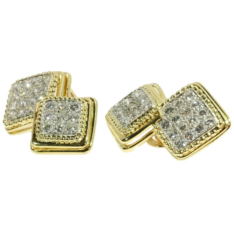 In each of these French Boucheron Estate earclips from 1950, two 18K yellow gold squares with 24 brilliant cut diamonds scattered over both fields of platinum merge into one another. A millegrain rim unfolds into a double terrace to enframe the