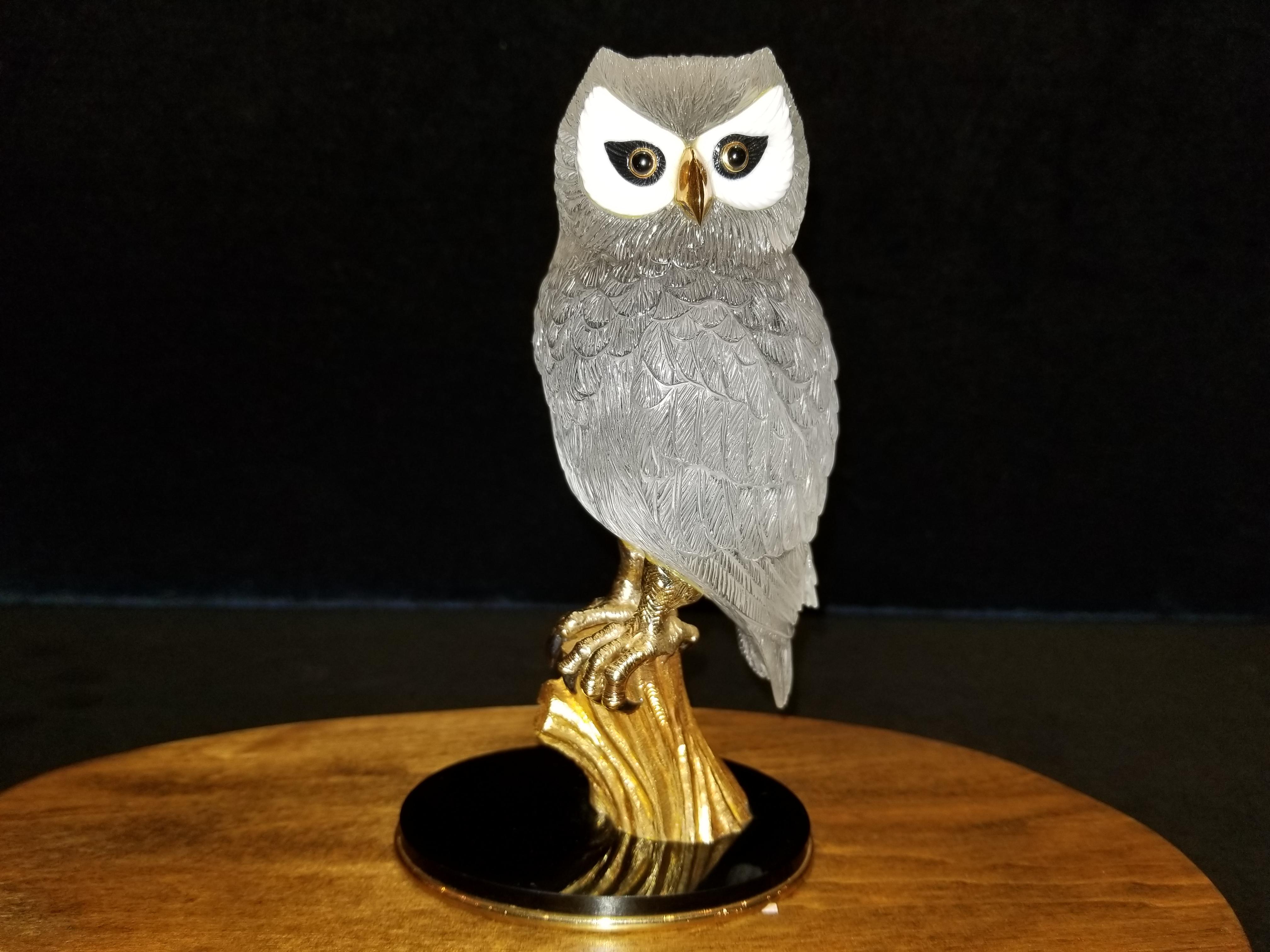 This fine hand carved rock crystal owl statue by Boucheron France is depicted by inset white and black onyx eyes with a gold beak. Gold feet with carved tigers eye talons. This magnificent Owl rests on a solid 18k gold tree trunk mounted to a black