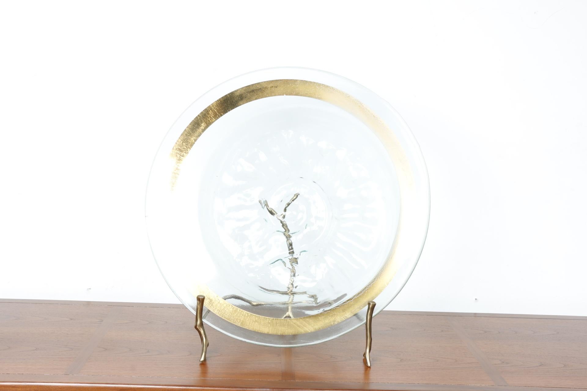 Bellissimo piatto in vetro spesso con design dettagliato. Accento in ottone intorno al piatto. Si trova su una base in ottone in stile ramo. Condizioni eccellenti. Ha una firma sulla base. Dettaglio in vetro di grande design. Non ci sono parti rotte