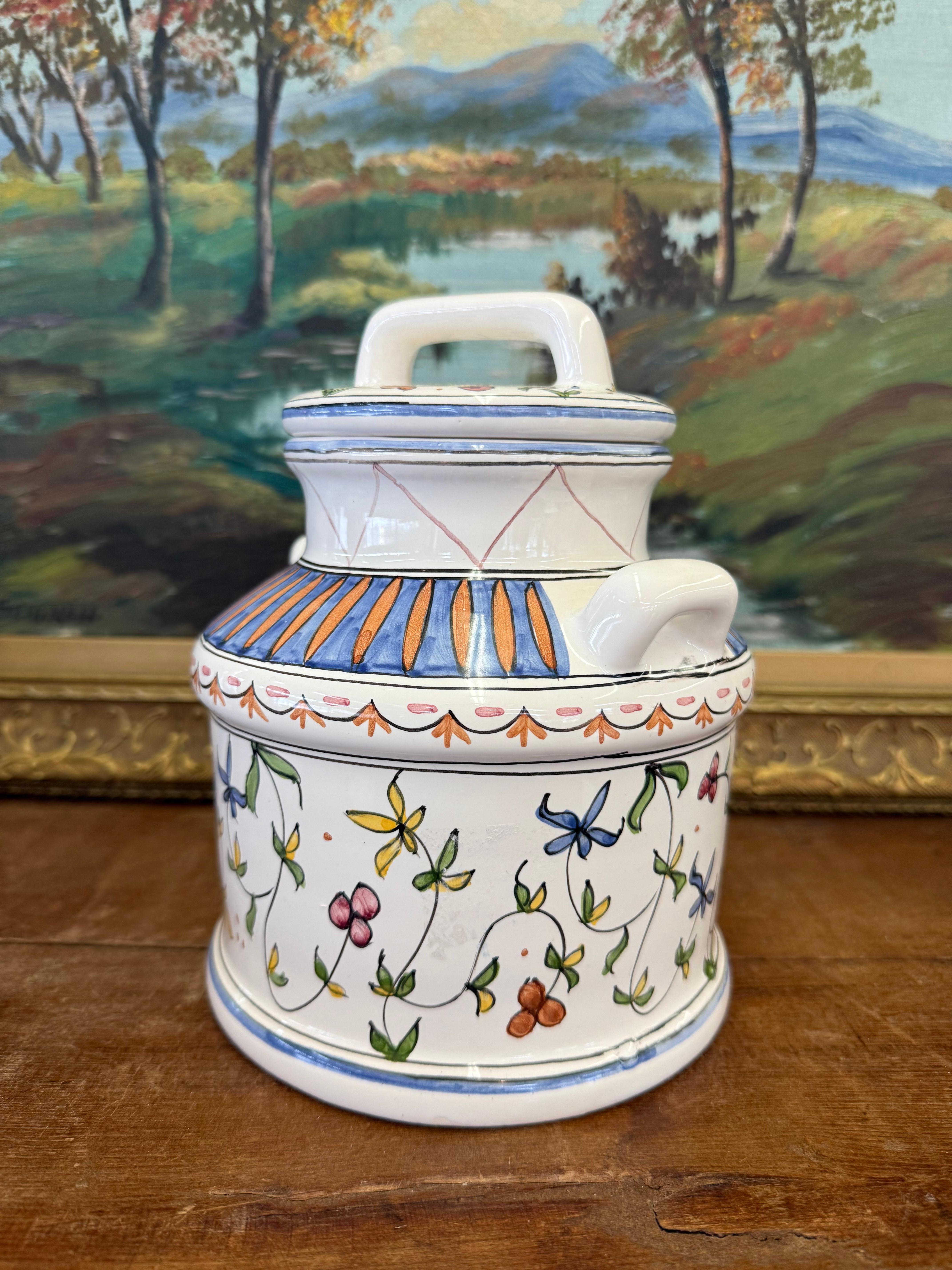 La ceramica presenta un corpo rotondo con un disegno decorativo di fiori e foglie colorate, con una serie di dettagli dipinti a mano. I fiori appaiono in tonalità di blu, giallo e rosso, creando un disegno vivace e artistico.
La ceramica ha uno