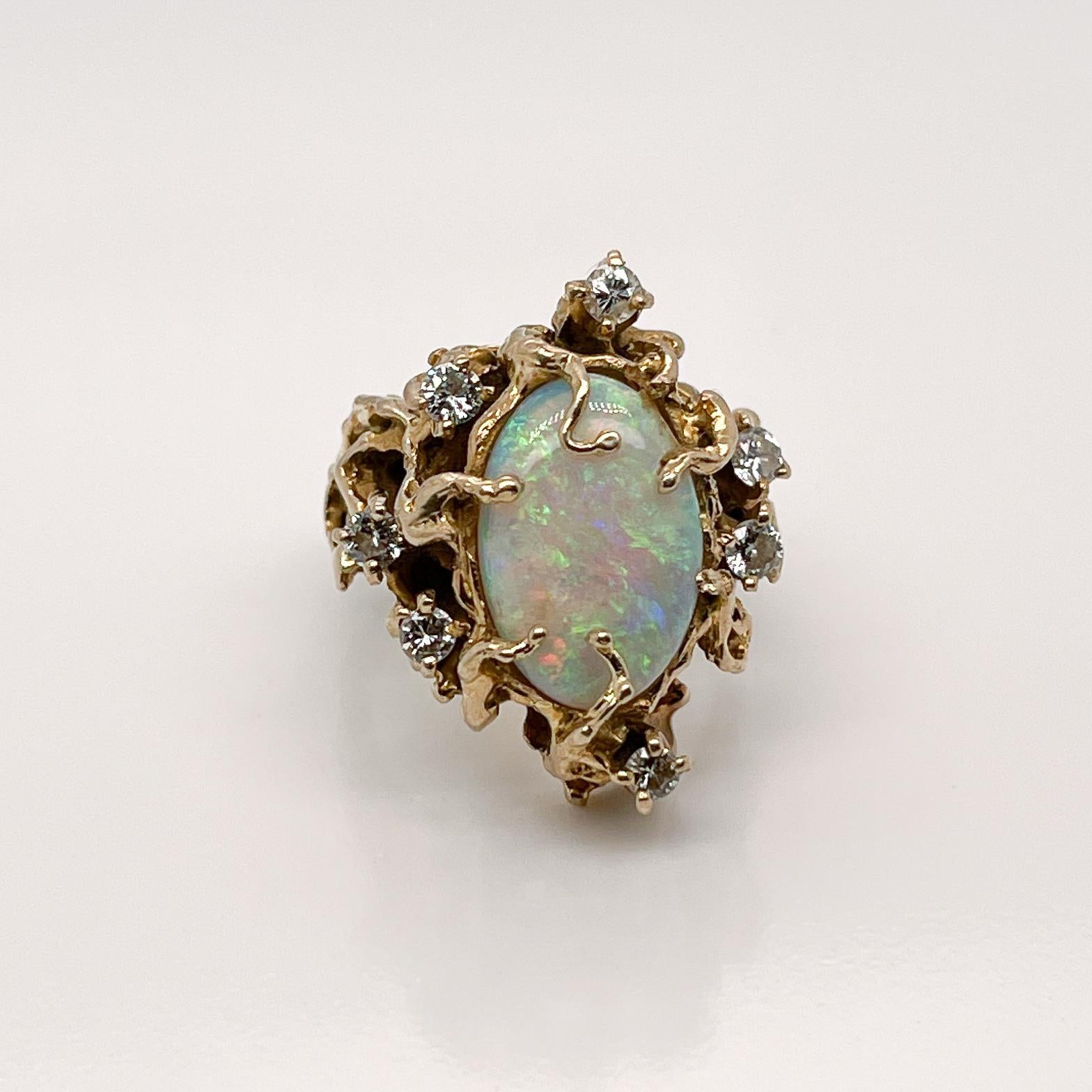 Ein sehr schöner signierter brutalistischer Opal- und Diamantring. 

Mit einem großen ovalen Opal-Cabochon in einer organischen:: gegossenen 14-karätigen Goldfassung. 

Der Opal wird von sieben kleinen runden Brillanten in Zackenfassung eingerahmt.