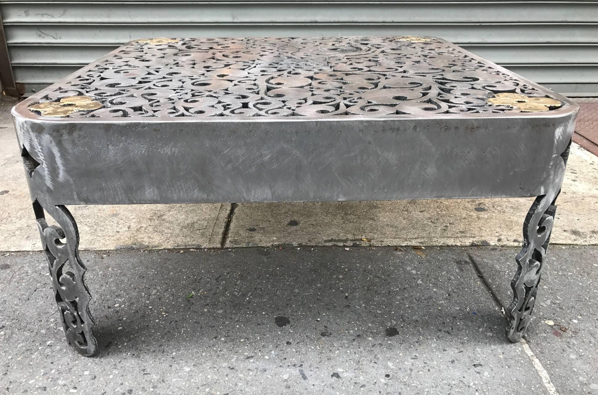 Signed Brutalist cut steel coffee table. The table is handmade torched cut and welded steel with a decorative pattern to the top. The top has bronze finished flowers on all four corners. Signed by the sculptor.
