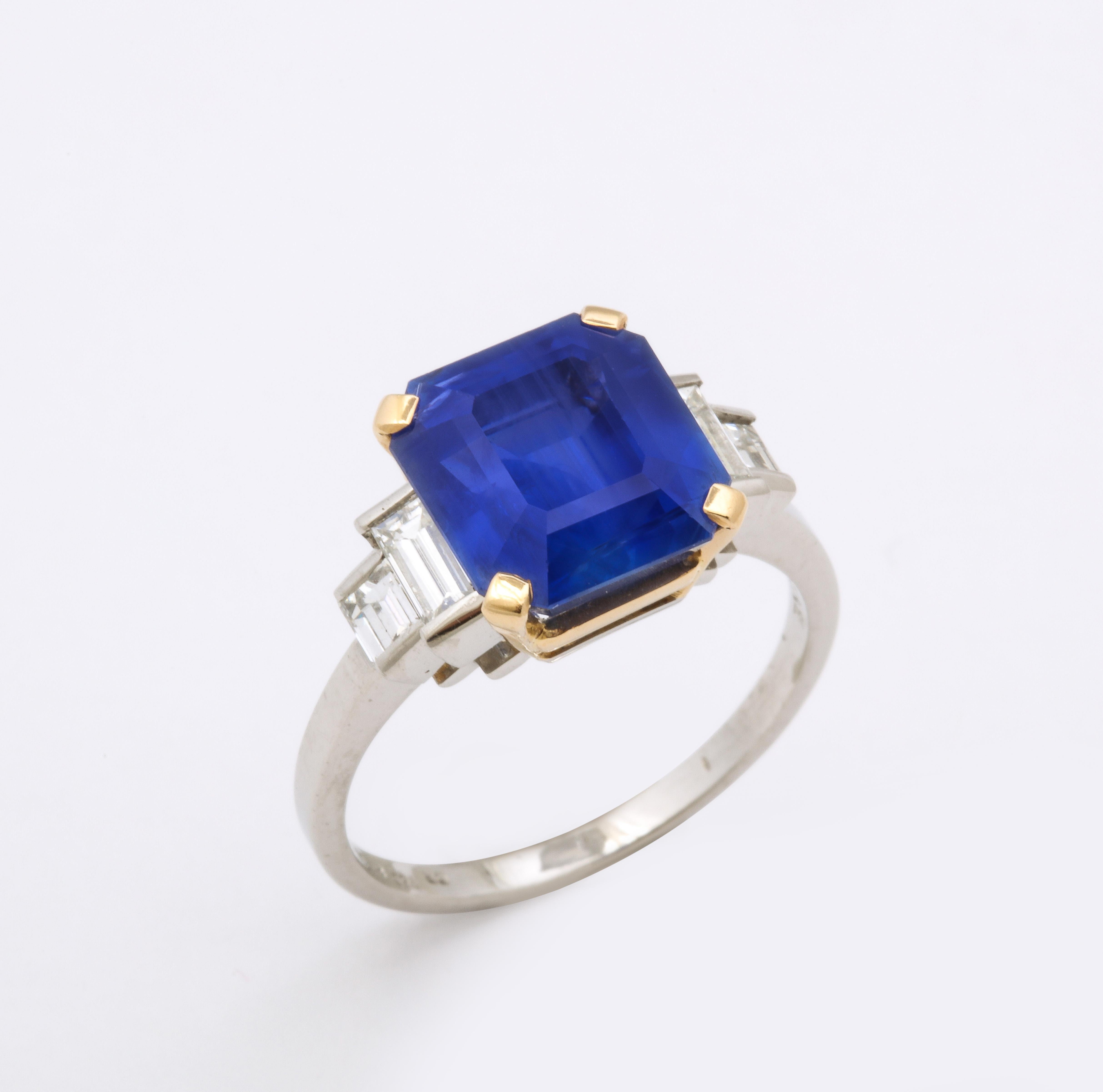 Bulgari Ceylon No Heat Sapphire and Diamond Ring in platinum and 18ct gold. Claw set with an emerald cut sapphire of 6.54 carats, accented by pairs of baguette cut diamonds. Signed Bvlgari. French import assay marks. Sapphire is of Ceylon (Sri