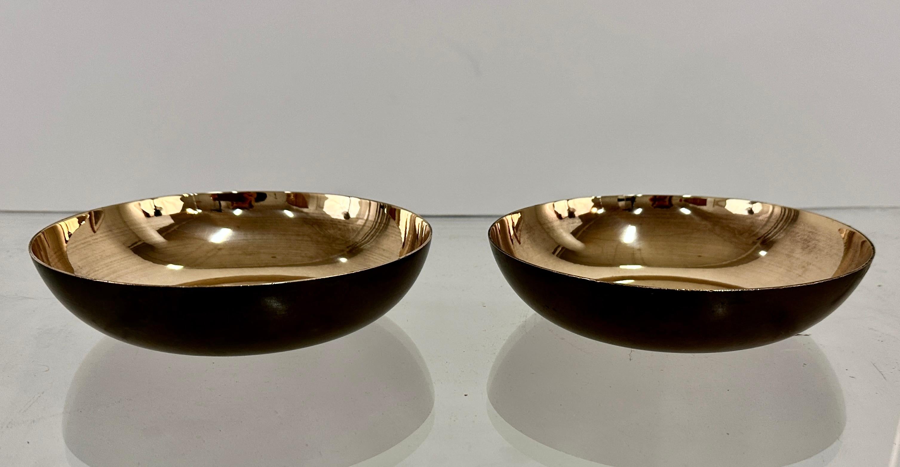 A pair of patinated bronze bowls with polished interiors by noted Arts and Crafts metalworker Carl Sorensen. Sorensen produced most of his work in Philadelphia in the early 20th century, and later became a designer for Tiffany Studios in New York.