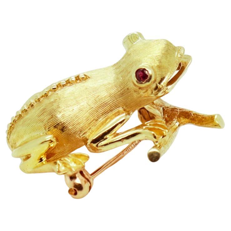A fine signed Mid-Century tree frog brooch.

In 14k gold.

With bezel-set faceted red spinel gemstone eyes.

Retailed by Cartier.

Marked to the feet with a serial number & 14K, with a maker’s mark to the interior, and Cartier to the pin stem.