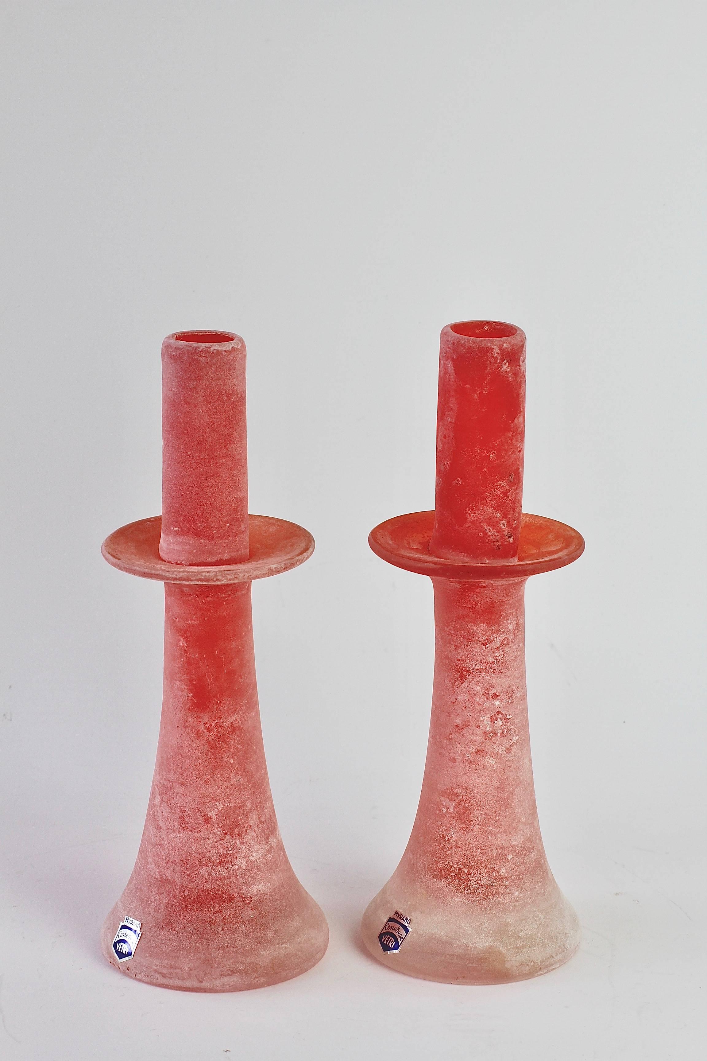 Beautiful and rare signed pair of Scavo glass candlestick holders by Cenedese Vetri Murano glass in collector's condition. Made of red Murano art glass featuring the 'scavo' technique, giving the glass the resemblance of historic roman glass which