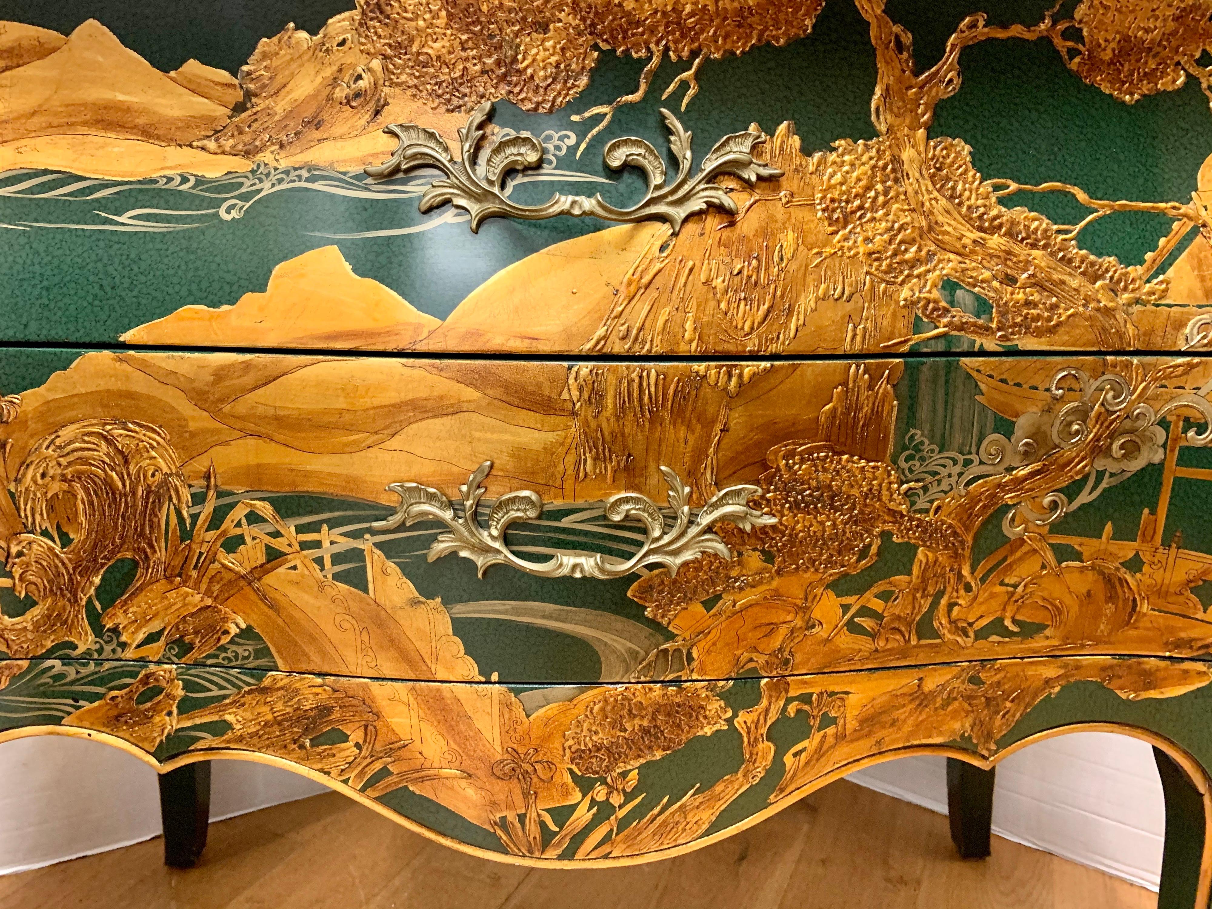 Stunning beautifully crafted chinoiserie two-drawer commode bombay chest by high-end maker John Widdicomb. Green lacquer finish with gold handpainted raised gilt decoration depicting a landscape of mountains and trees. With cast brass pulls and