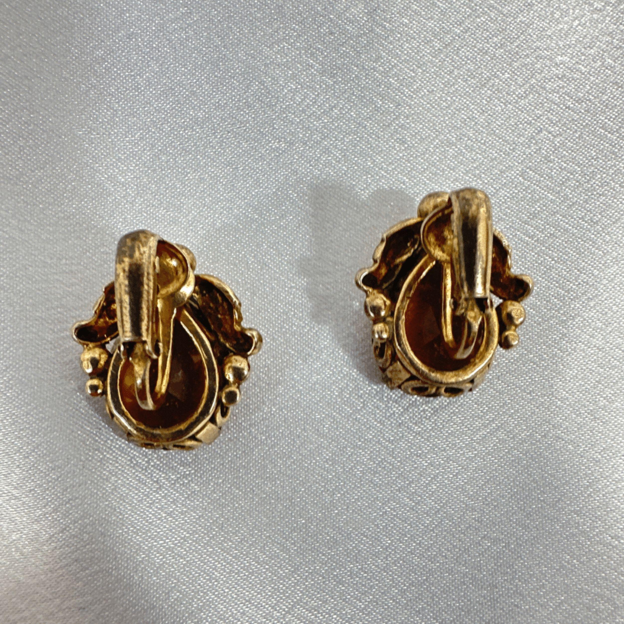 A captivating blend of artistry and brilliance, these vintage Cini earrings showcase sterling silver craftsmanship paired with striking orange crystals. The stones, rich with an amber-like glow, capture and reflect light beautifully, creating a