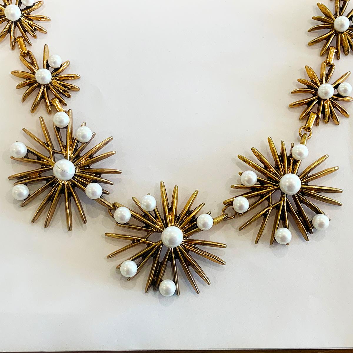 Authentic signed Oscar De La Renta starburst Necklace, in joined gilt stars of different sizes, highlighted with Faux Pearls also in varying diameters. All complete and perfect, Claw Clasp and the usual adjustable length having the Gilt tab Hallmark