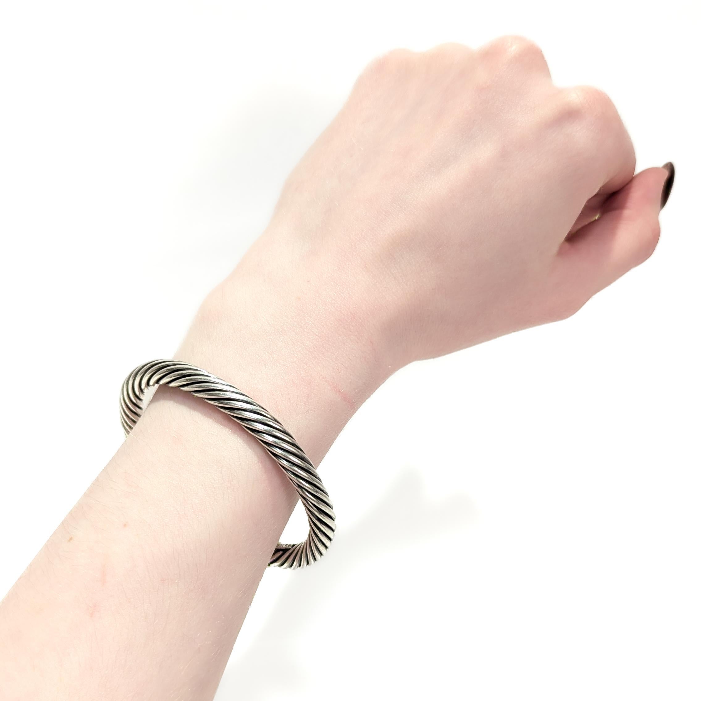 A fine signed silver & gold cuff bracelet.

By David Yurman.

In sterling silver and 14k gold.

In the 'Classic Cable' pattern.

The cuff is 7mm diameter with 14k gold domes to each terminal.

Marked to the interior of the bracelet.

Simply a