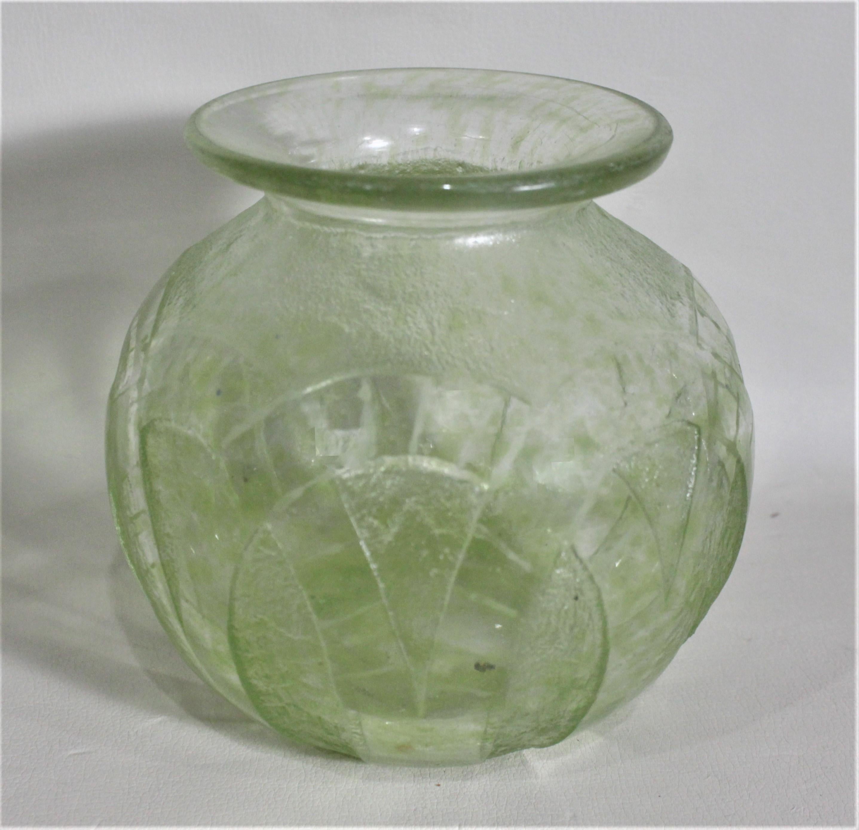 Diese grün gefärbte und mit Säure geätzte Vase im Art déco-Stil wurde vermutlich um 1920 in Frankreich hergestellt. In die Seiten dieser gedrungenen, bauchigen Vase ist ein umgekehrtes Rautenmuster tief eingraviert, das außen strukturiert ist. Das
