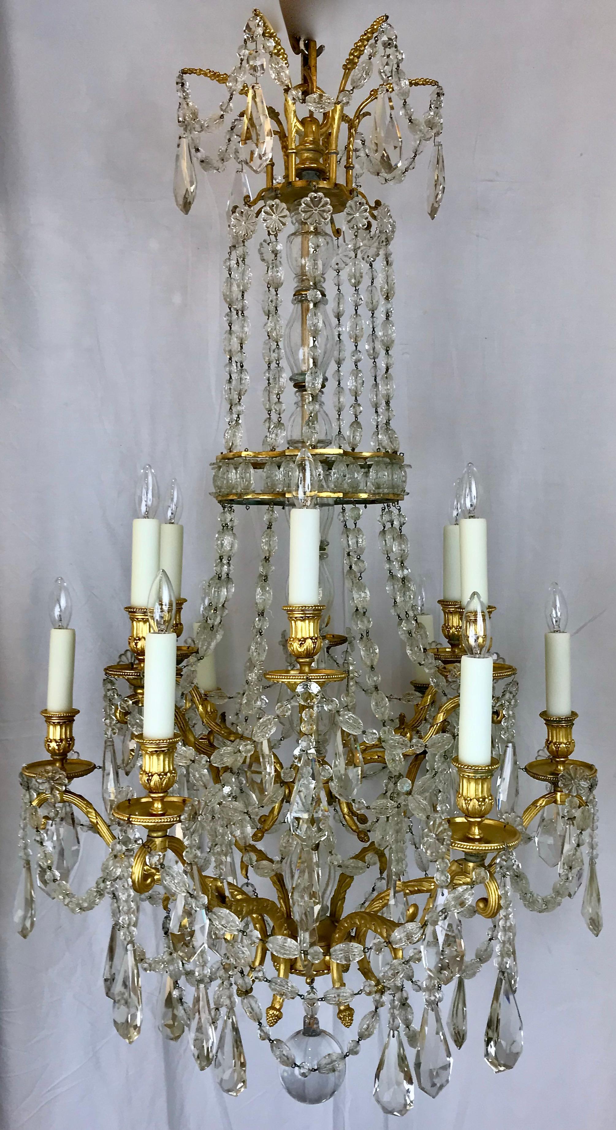 This fabulous signed twelve light gilt bronze and crystal chandelier by Edward F. Caldwell and Company is of the finest quality. It features  beautifully chased Neo-classical motifs including acanthus leaves, acorns and berries. It can be found