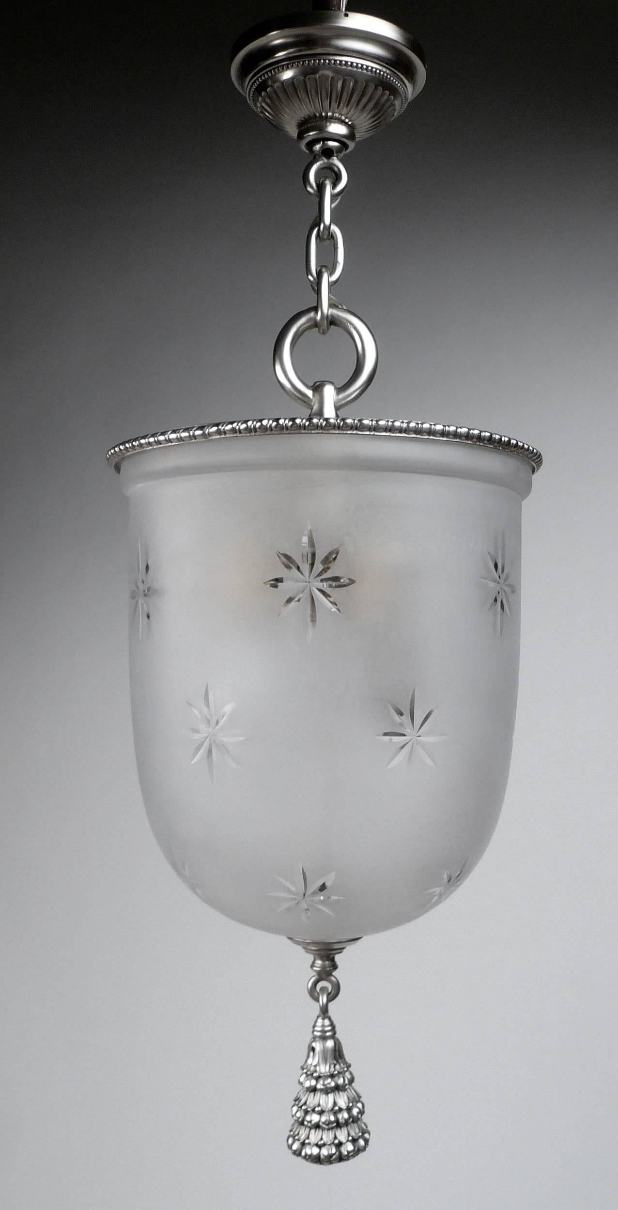 This hanging pendant fixture features a star pattern cut and frosted glass shade. The finely cast silvered bronze mounts include a hanging fruit motif tassel. It is equipped with three standard base light sockets.