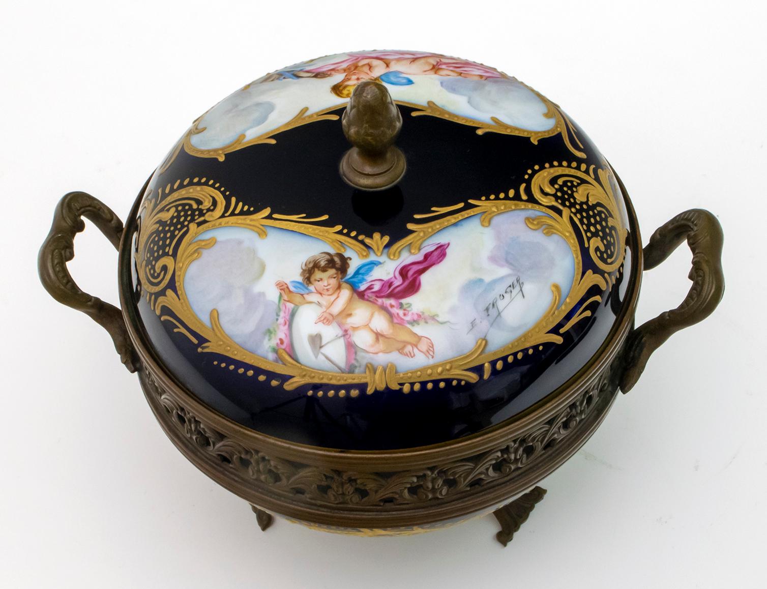 Cobalt blue and gold with two cartouches on the lid each with a winged cherub and a dove signed E. Froger. Perforated bronze strap with handles which is attached to the bottom of the bowl which is housed in a bronze base. Sevres marks on the inside