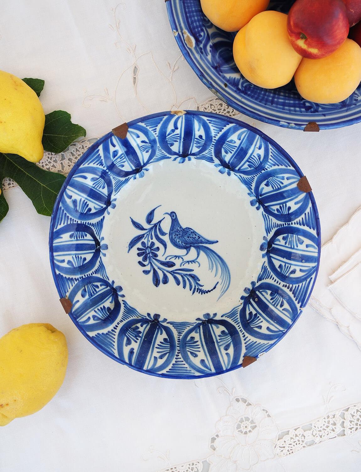 This beautiful Sicilian shallow bowl was made in the early 1800s. It has been hand-painted with a beautiful bird and pattern around the rim. The initials M.H.V of the artist who made it have been painted on the side. This shallow bowl was found in a