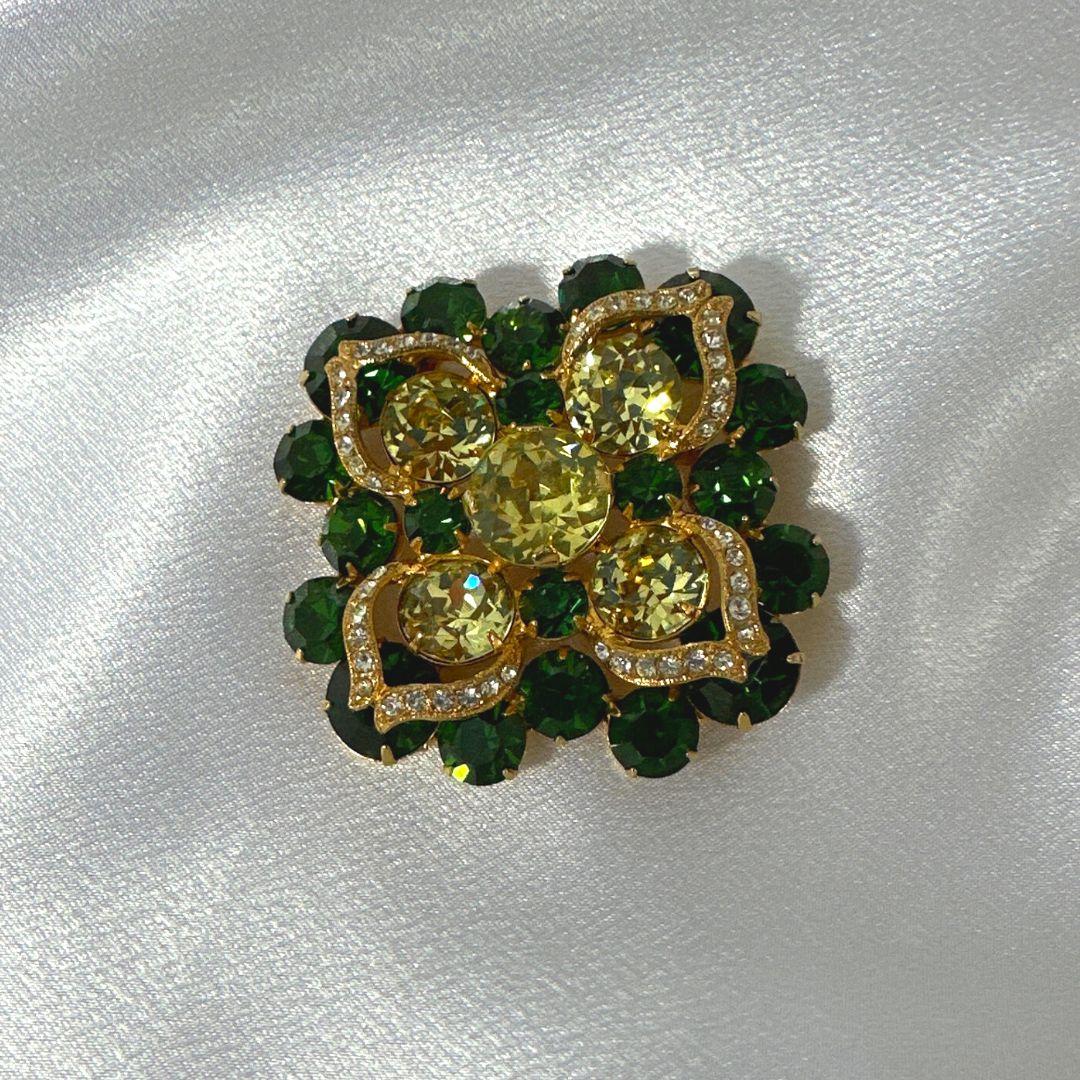 Hight: 2″

Width: 2″

Bin Code: B5 / P3

Step into the world of vintage elegance with this exquisite Antique Vintage Eisenberg Brooch. Adorned with mesmerizing green and gold glass accents, along with sparkling rhinestones, this brooch is a true