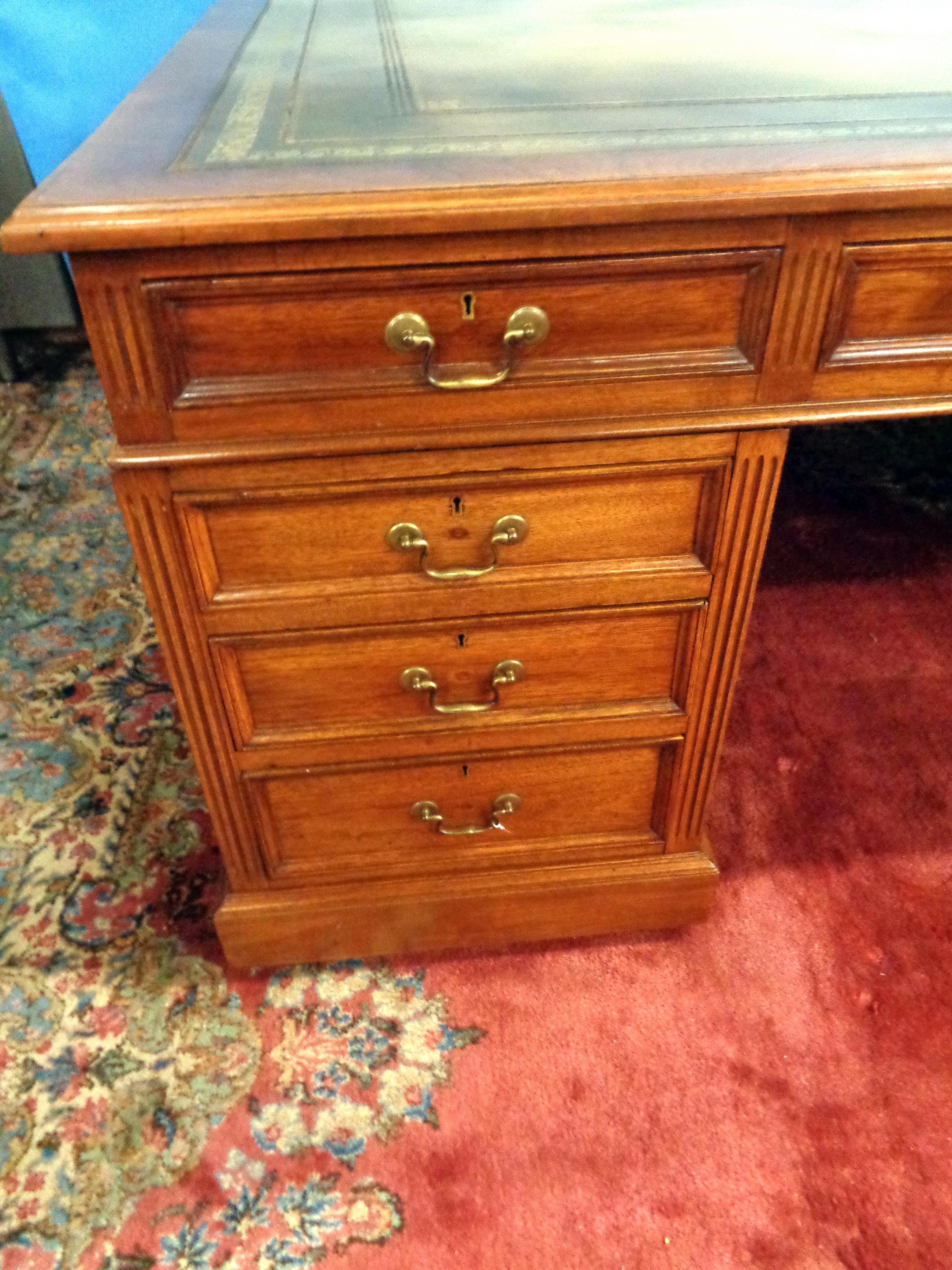 Fine English large mahogany partners desk with gold tooled leather top by noted maker Maple & Co.. There are drawers and cupboards on both sides and bail pulls on the drawers. This is a beautiful highly functional desk with a large central opening.