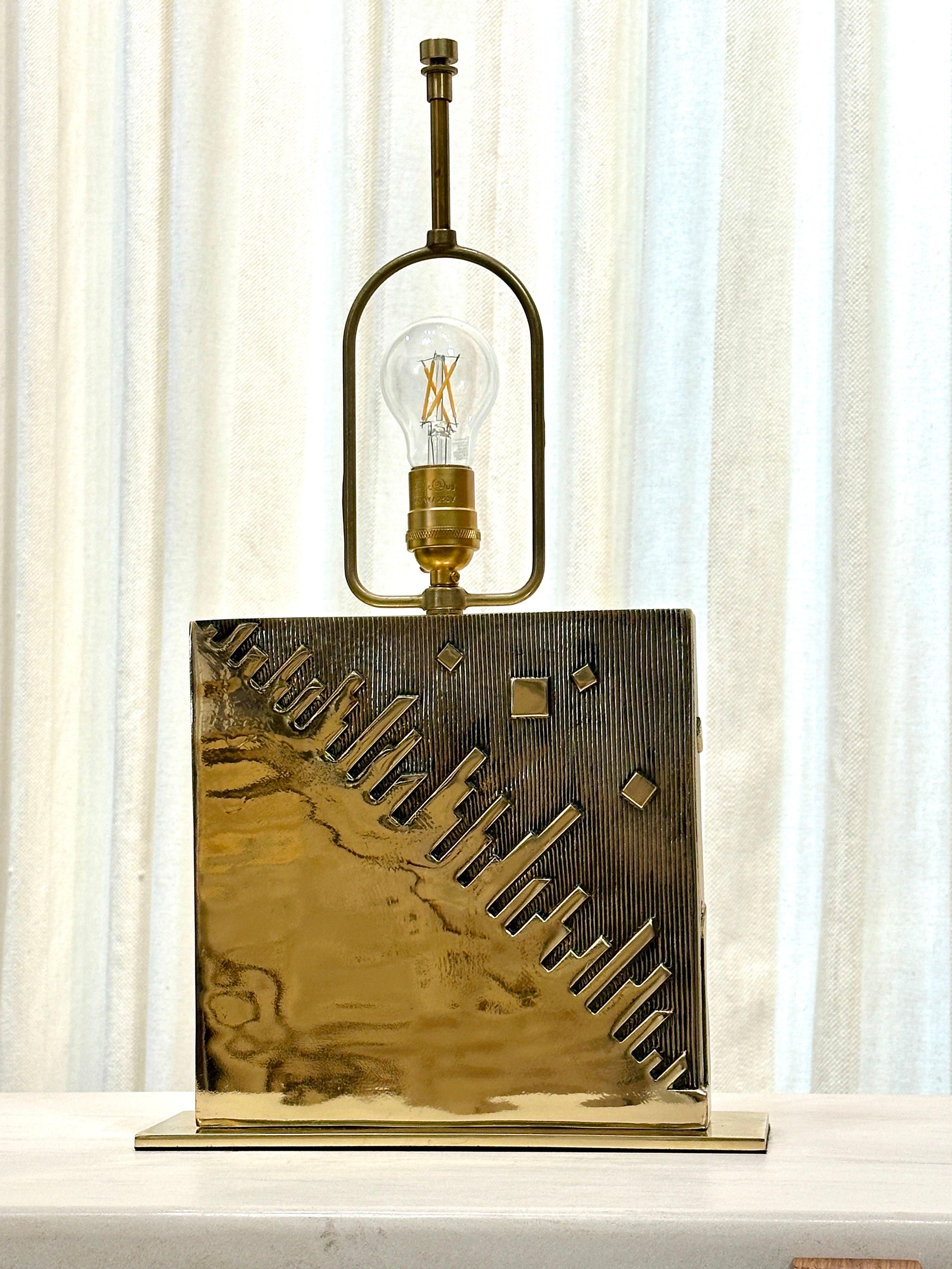 Sculptural Bronze lamp by Esa Fedrigolli (signed) with a very deep bas-relief depicting a city skyline on front and back.  The brass is shiny and beautiful, ready to use as it has been rewired for US with silk cable and new plug and socket.