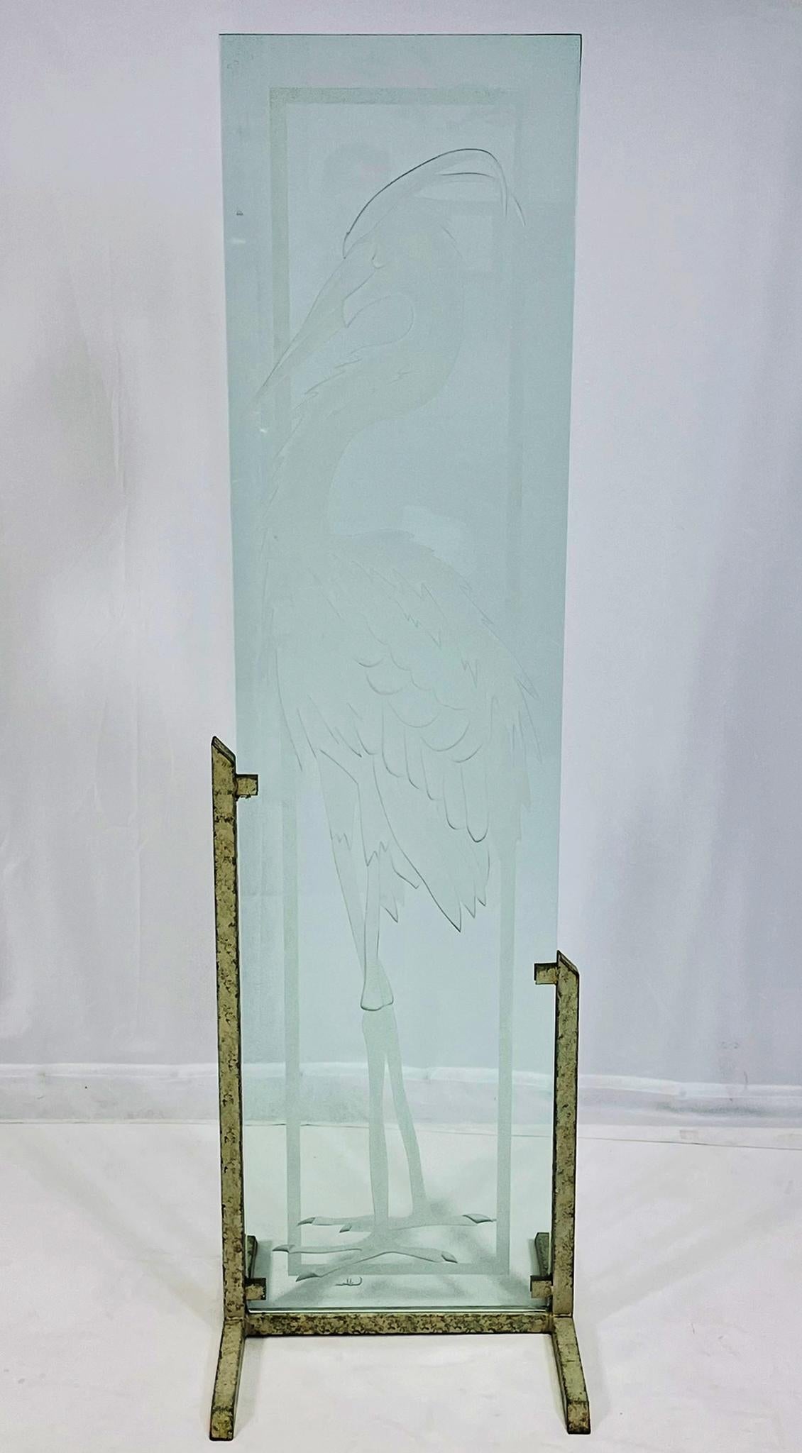A striking and tall etched glass panel sculpture, featuring the stylized image of a heron or crane rendered in deep intaglio carving with fine feather and plumage detailing. The bird is framed within a rectilinear border, giving the work an