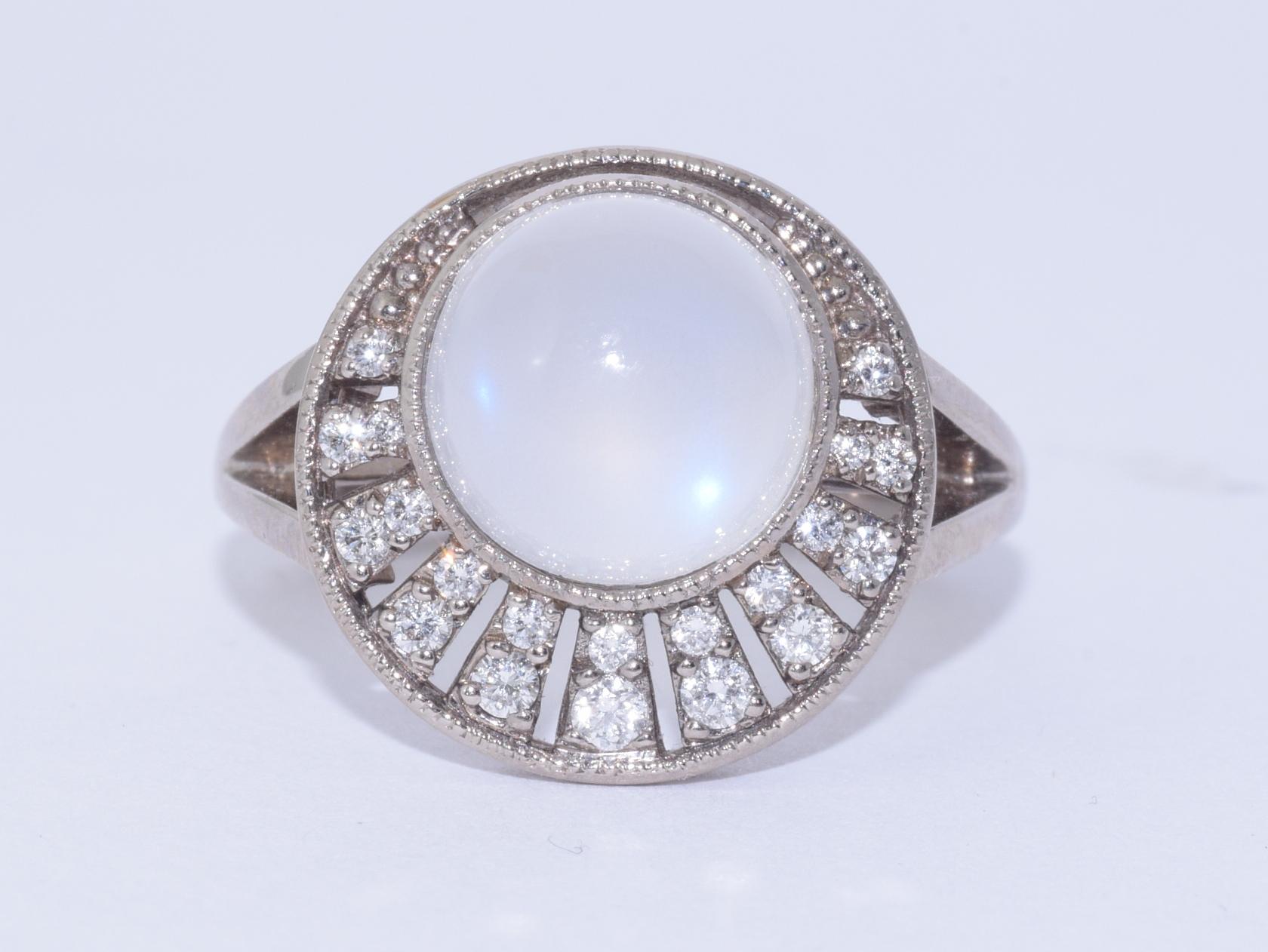 Rays of round diamonds totaling approximately 0.18 carats emanate from a round cabochon moonstone weighing 3.20 carats mounted in 18 karat white gold. Finger size 6.
Moonstone 9mm. Top of ring 15mm.

Fred Leighton is renowned for extraordinary