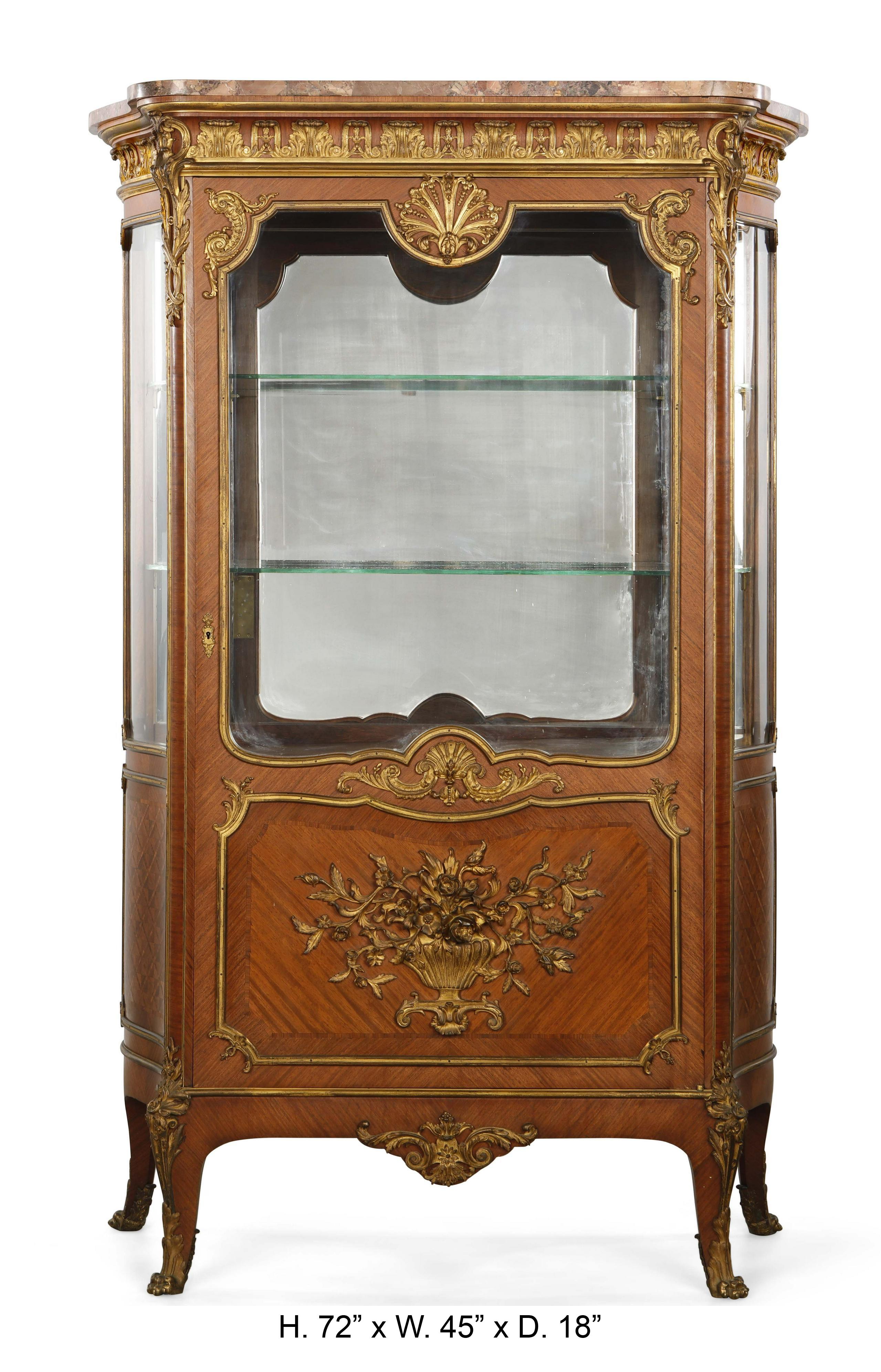 Exquisite French Louis XV style gilt bronze mounted mahogany vitrine cabinet. Ormolu signed FB. 
Late 19th century.

The spectacular vitrine is surmounted by a shaped mottled marble top, above an ormolu mounted frieze decorated with leaf-tip,