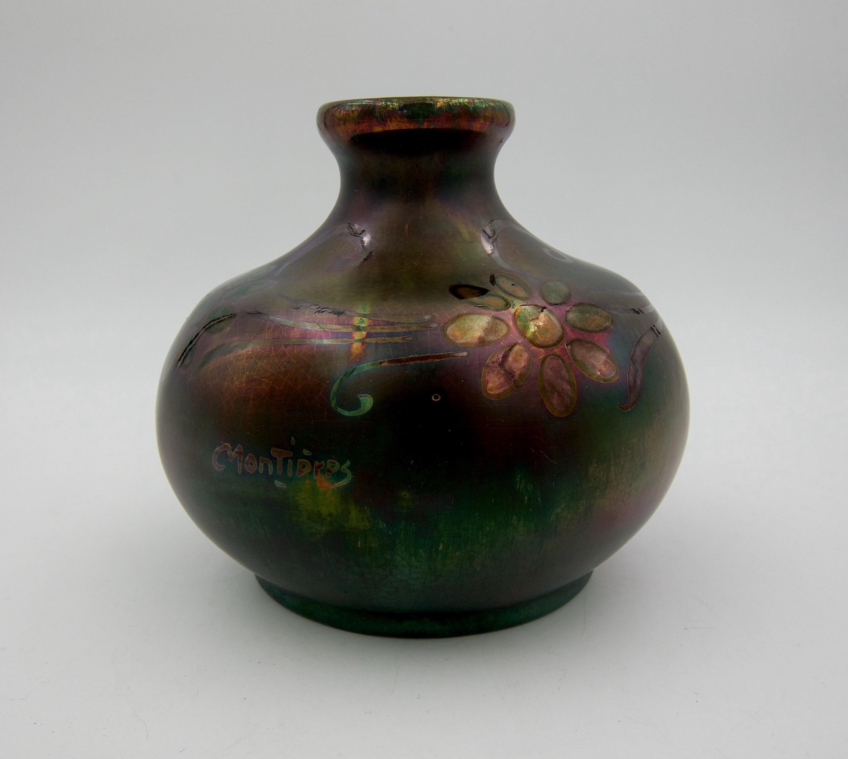 A signed French art pottery vase with a metallic luster glaze from the Montières workshop, dating circa 1920s. The French faience Art Nouveau vase is decorated with an overall green, purple, and dark maroon iridescent glaze. Hand-painted flowers and