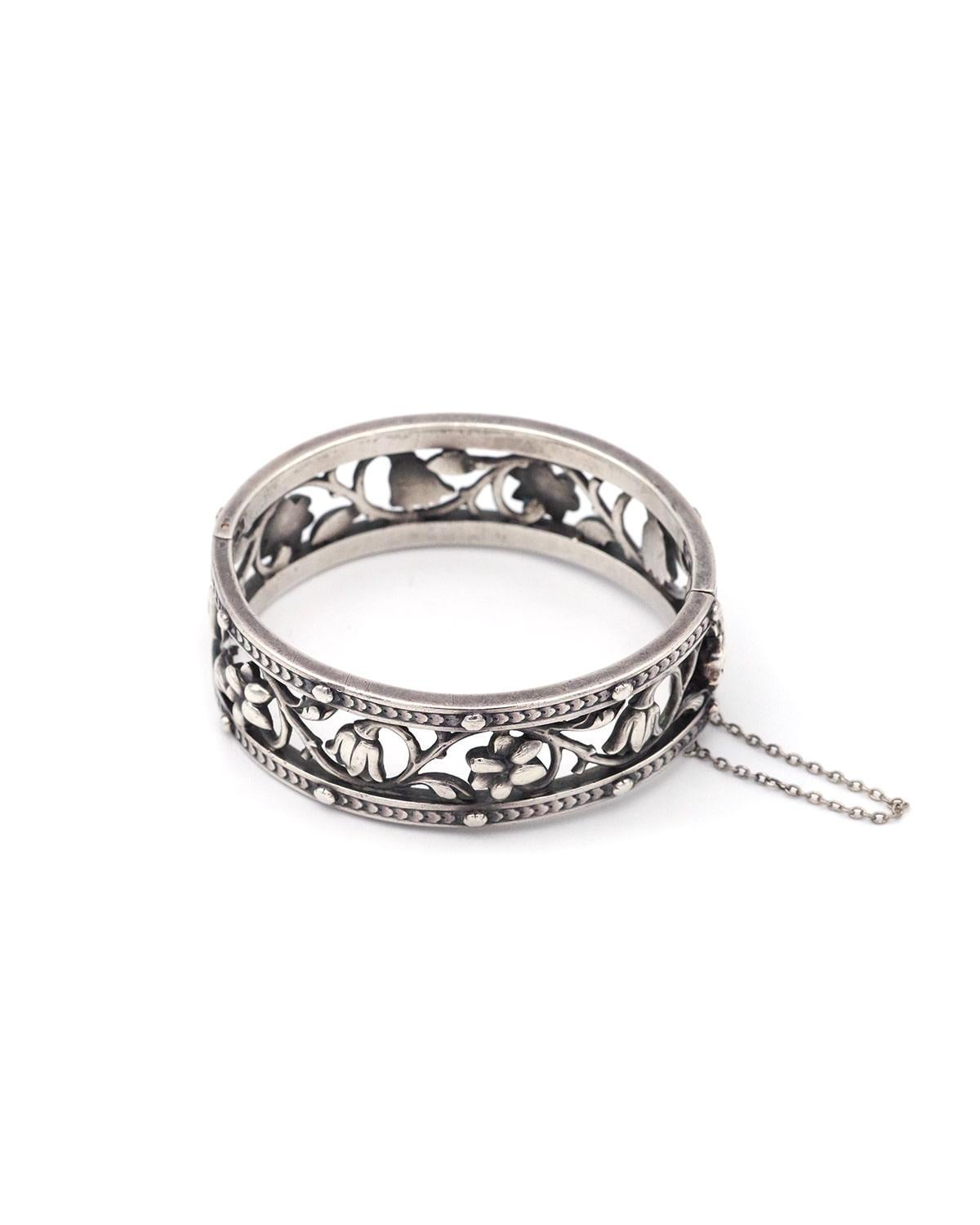 Froment-Meurice cuff bracelet in silver and gold . Wide, rigid bracelet decorated with flowers framed by two friezes of chiseled leaves, punctuated with silver beads. The clasp is gold and bears the signature. This piece of jewelry was probably