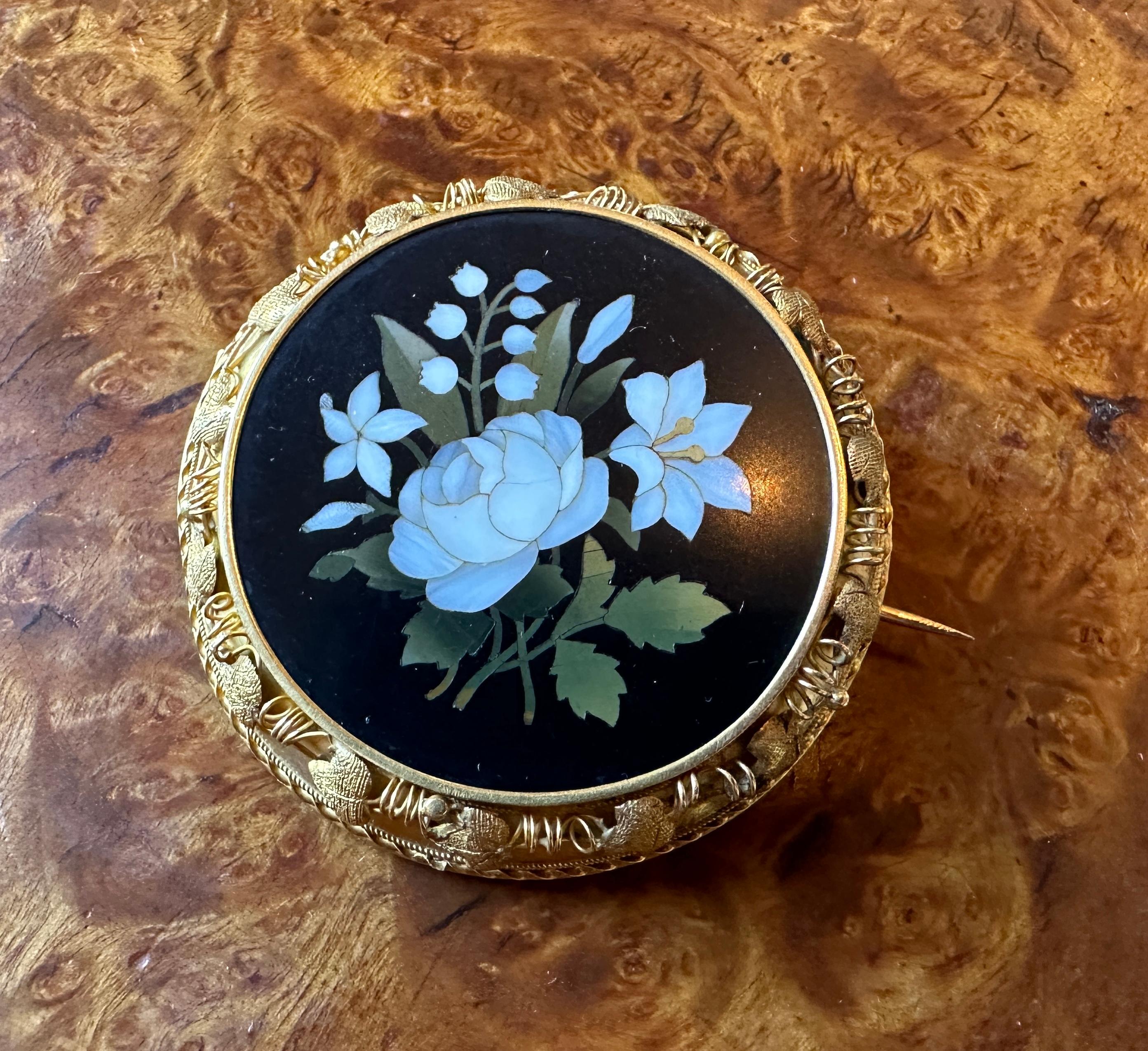 Concediti una spilla firmata Giocondo Torrini in Pietra Dura di qualità museale, in oro 14 carati, con pietre semipreziose intarsiate che creano un mosaico di fiori, tra cui una splendida rosa, gigli e mughetti, e con il bordo a foglia scorrevole