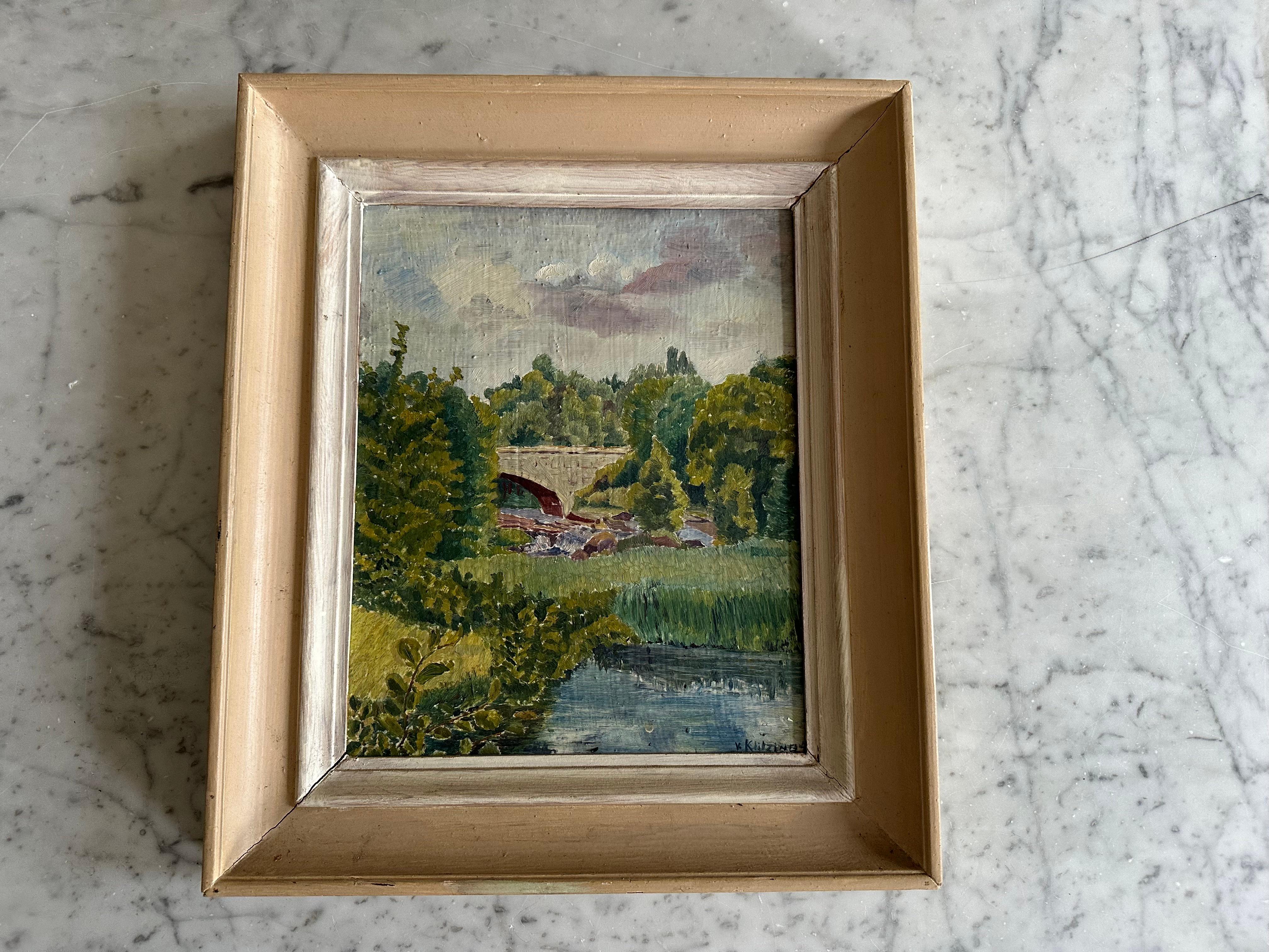 Questo dipinto a olio originale tedesco, firmato e datato circa 1934, è un vivido esempio di arte paesaggistica impressionista del primo Novecento. La composizione presenta un antico ponte in pietra che attraversa un fiume che scorre dolcemente,