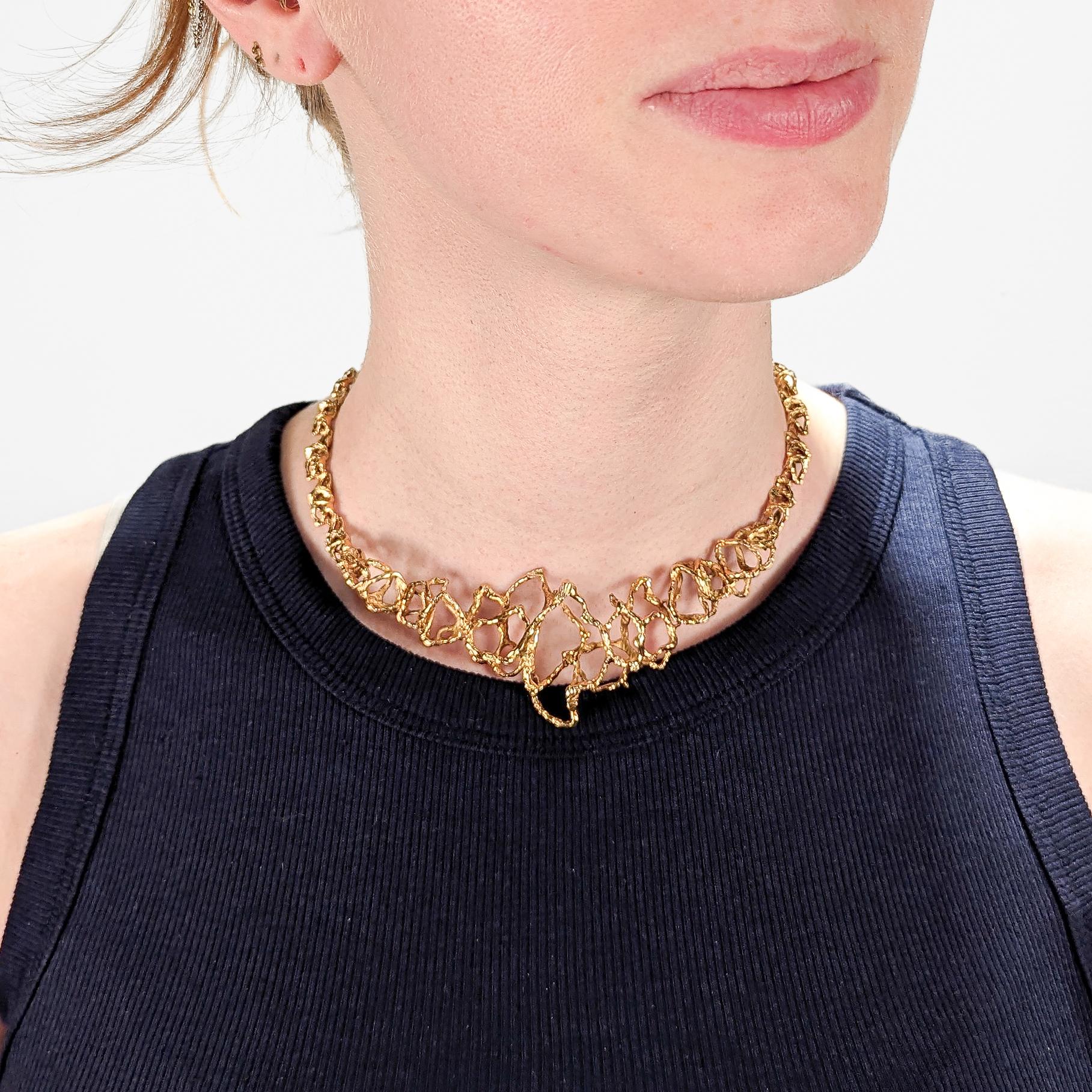 Una raffinata collana modernista svizzera.

Da Gübelin.

In oro giallo 18 carati.

Con maglie traforate brutaliste graduate e fatte a mano. 

In una vera dimensione a girocollo con un forte richiamo stilistico ad Arthur King e Andrew Grima.

Un