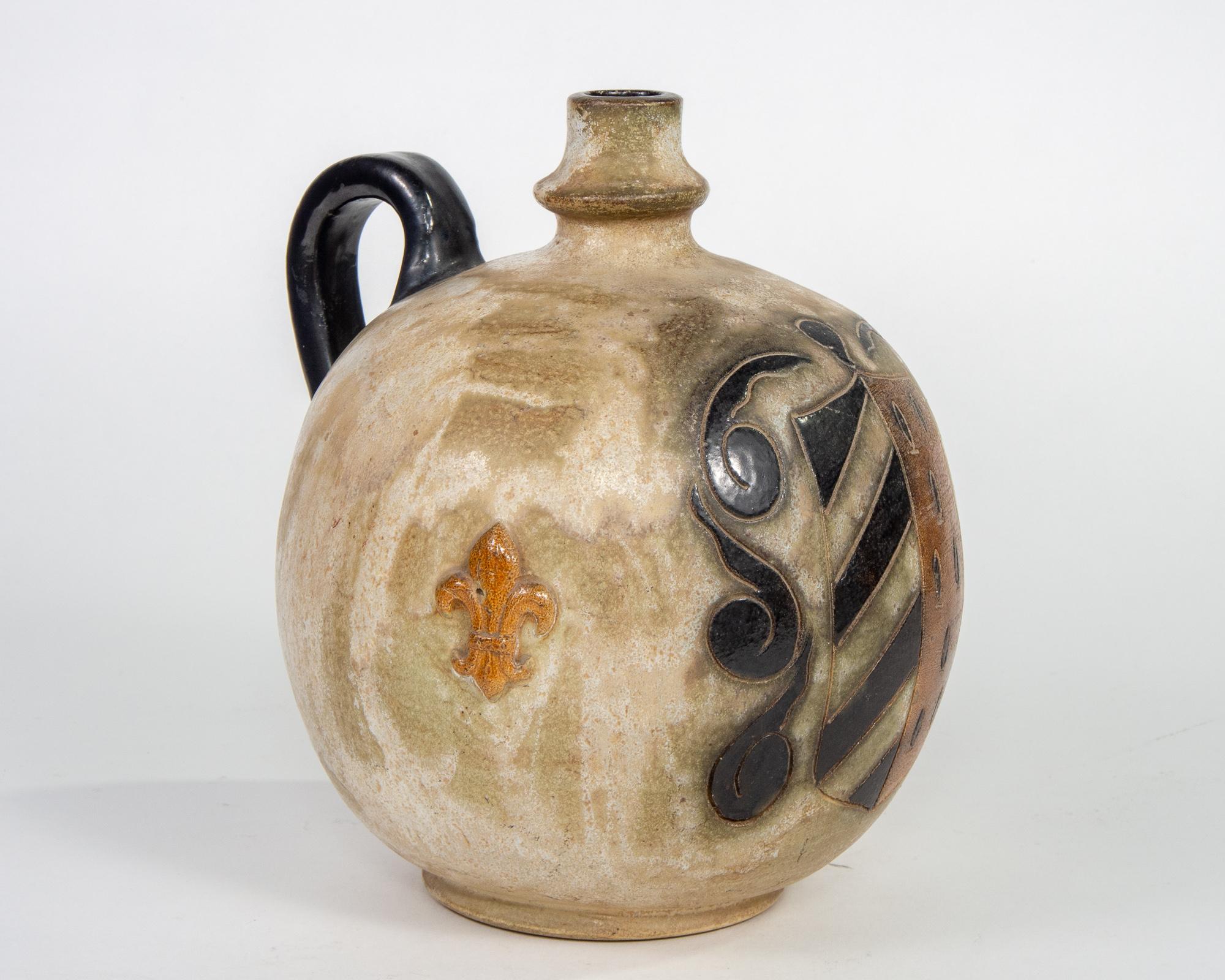 Midcentury ceramic jug by Guerin of Bouffioulx, Belgium has a globe-shaped body, black handle and narrow neck. Design is etched and glazed depiction of shield and fleur-de-lis. Etched signature on underside of base.