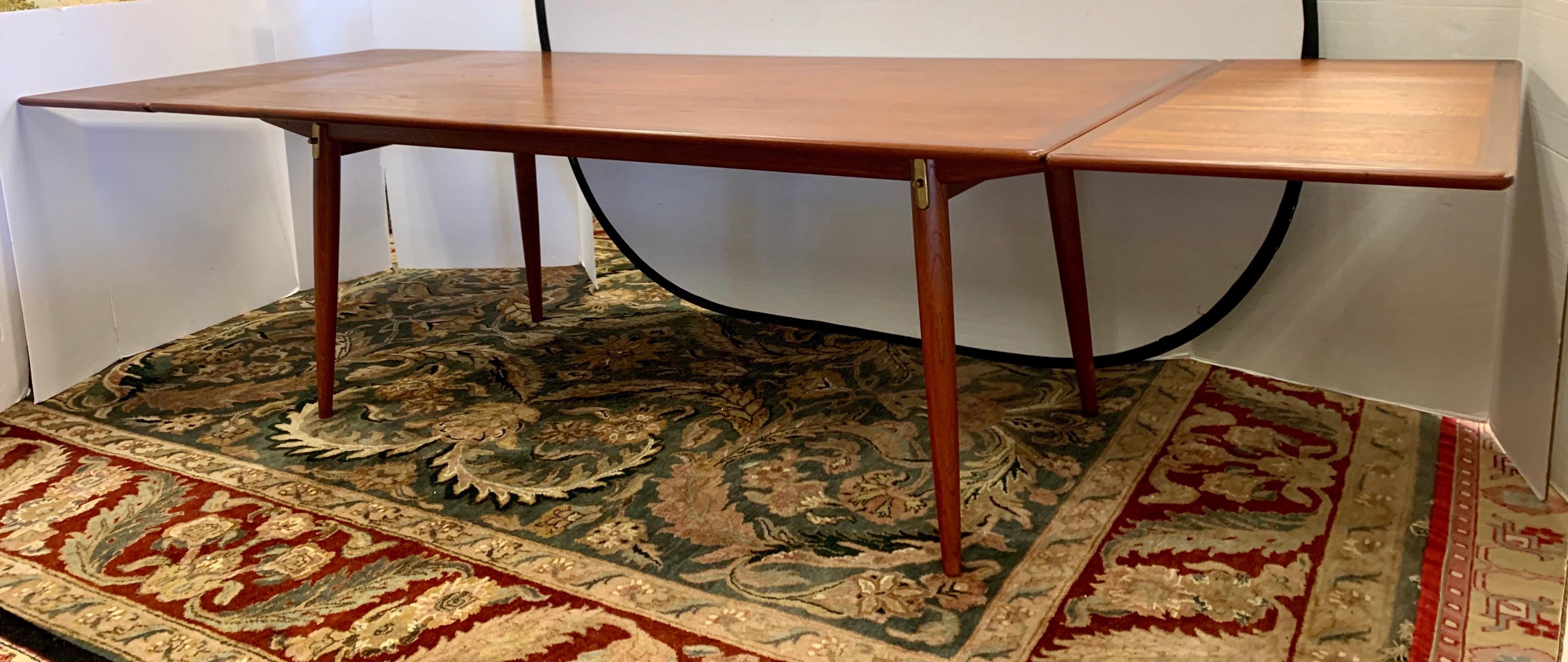 An ultra rare signed Johannes Hansen, Hans Wegner designed rectangular dining table with a teak top concealing steel and brass pullouts and an innovative hidden leaf storage on a fumed oak base with splayed, tapered dowel legs. The leaves are hidden