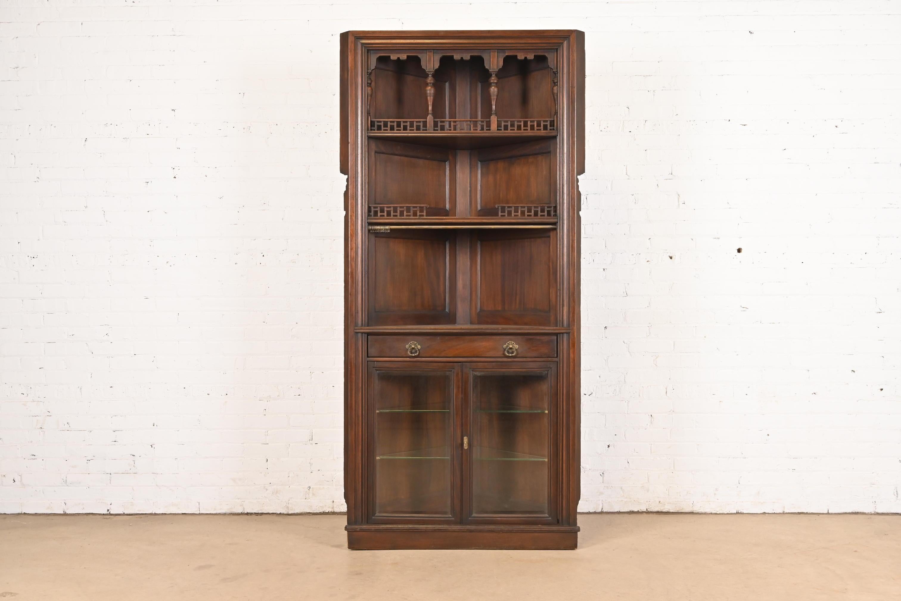 An outstanding antique Eastlake Victorian corner bar cabinet, dining cabinet, or display cabinet

By Herter Brothers (signed with branded mark)

USA, Circa 1890s

Carved mahogany, with glass front doors, and brass hardware. Cabinet locks and key is